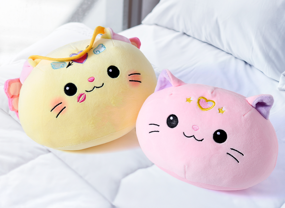 Two Nyan Nyan plushies on a white bed 