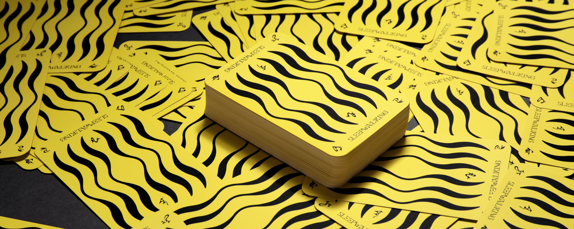 Photo showing all of the Sleepwalking cards spread out. They are all face down showing their yellow and black backs.