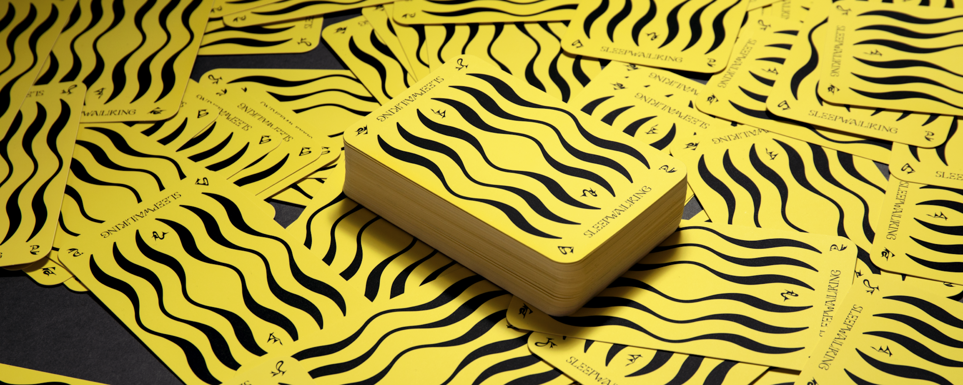 Photo showing all of the Sleepwalking cards spread out. They are all face down showing their yellow and black backs.