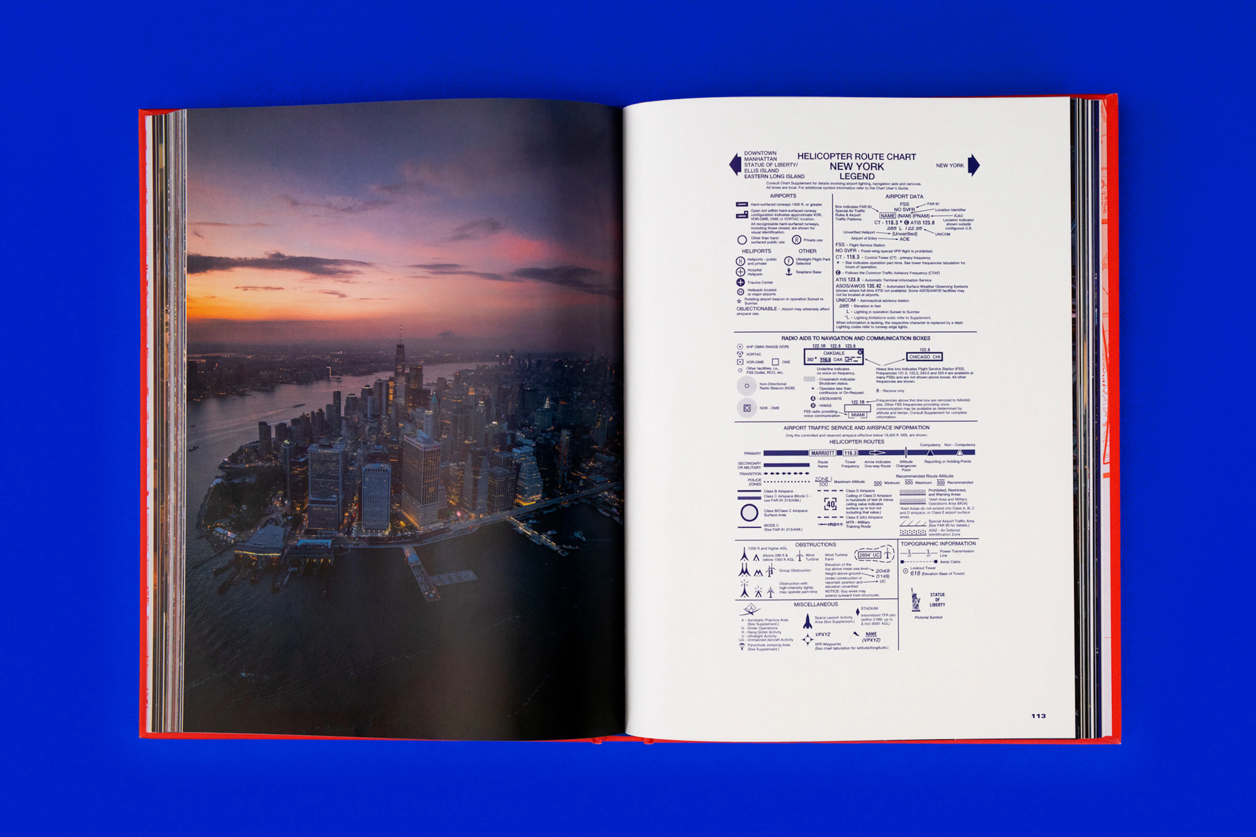 Overhead photo showing a spread from the book with a sunset NY skyline photo on the left and blue text on the right. The book is lying on a cobalt blue seamless. 