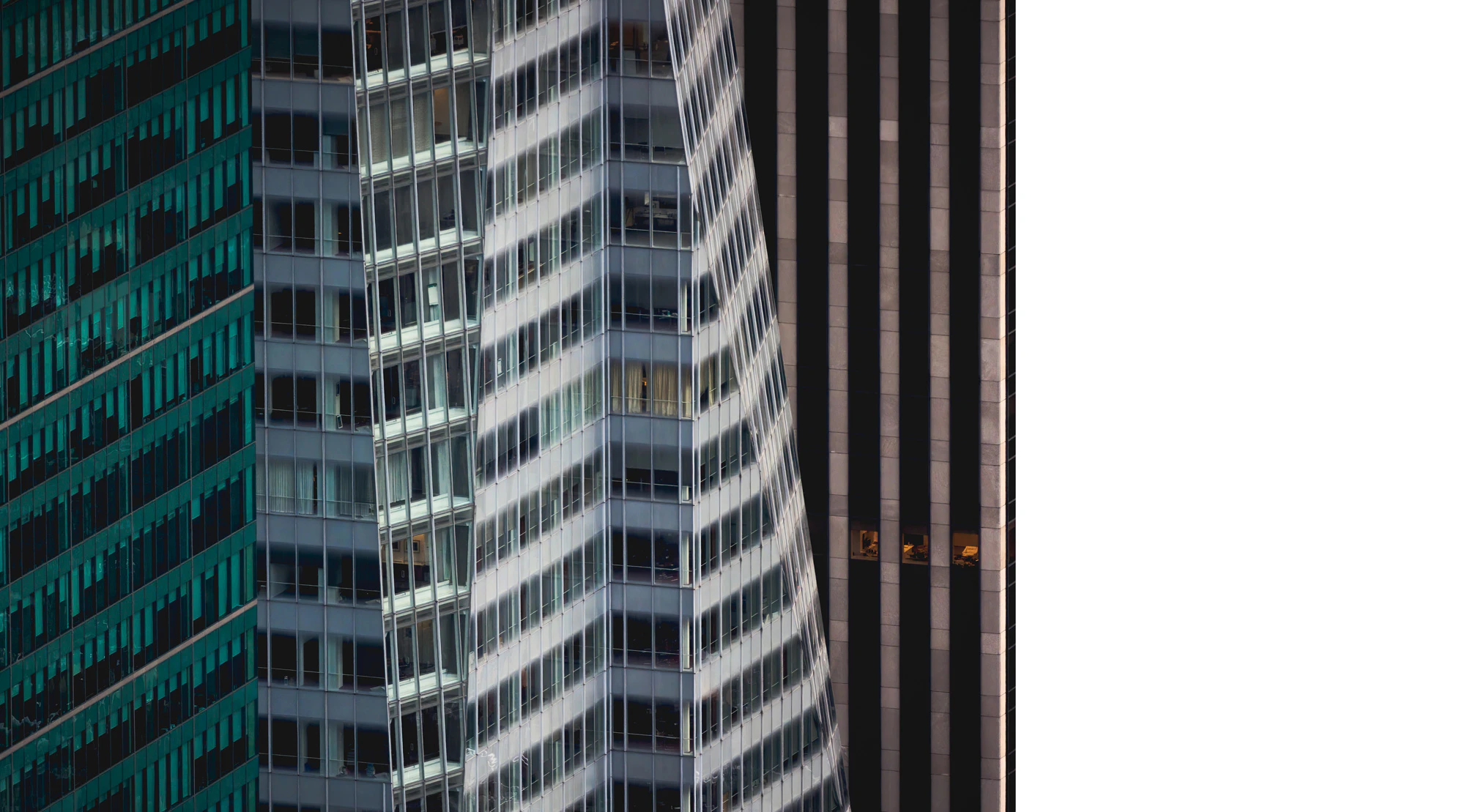 Photo showing a close-up of three buildings each with its own texture and color. The first one looks teal, the second light gray, and the third a warm mid-gray.
