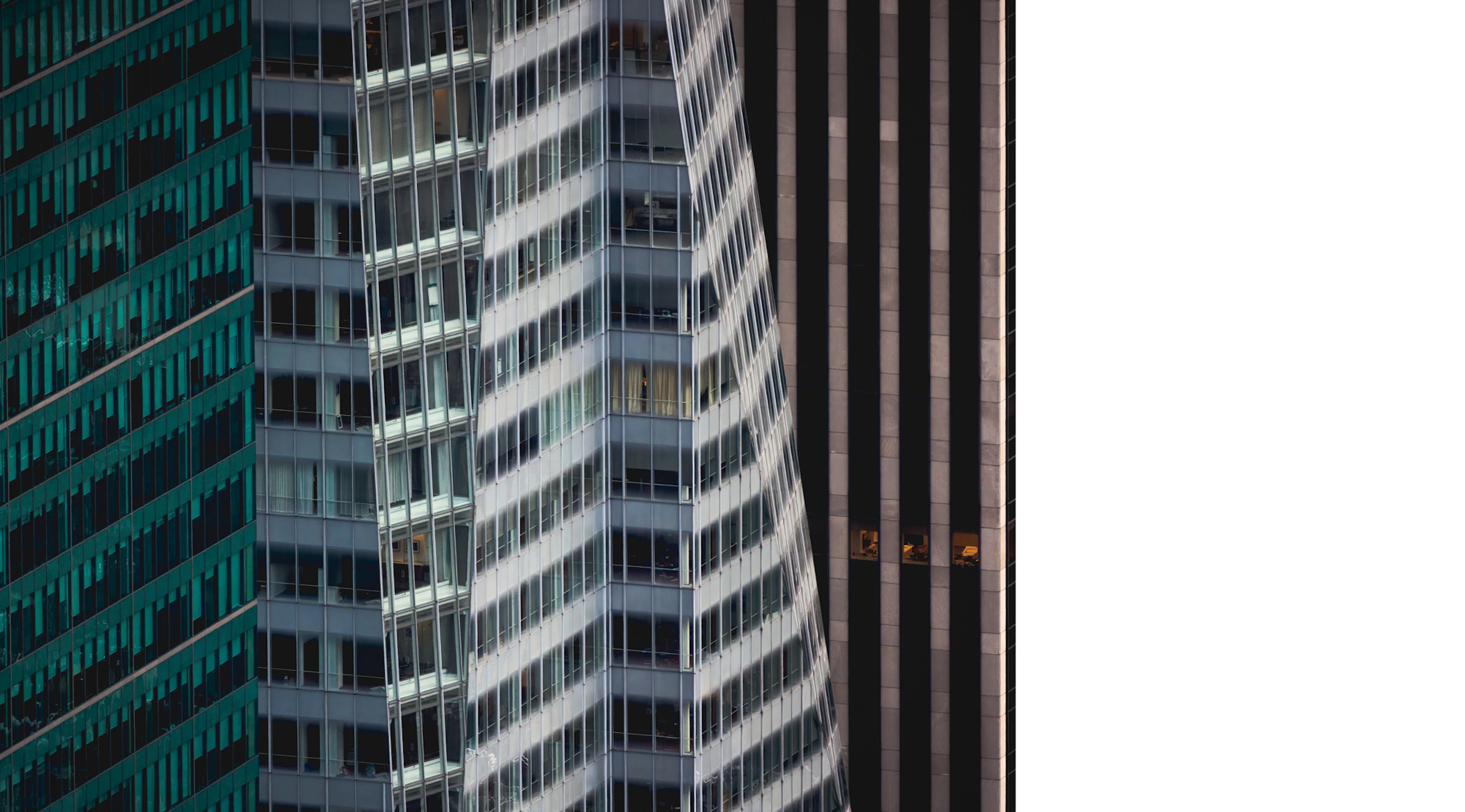 Photo showing a close-up of three buildings each with its own texture and color. The first one looks teal, the second light gray, and the third a warm mid-gray.