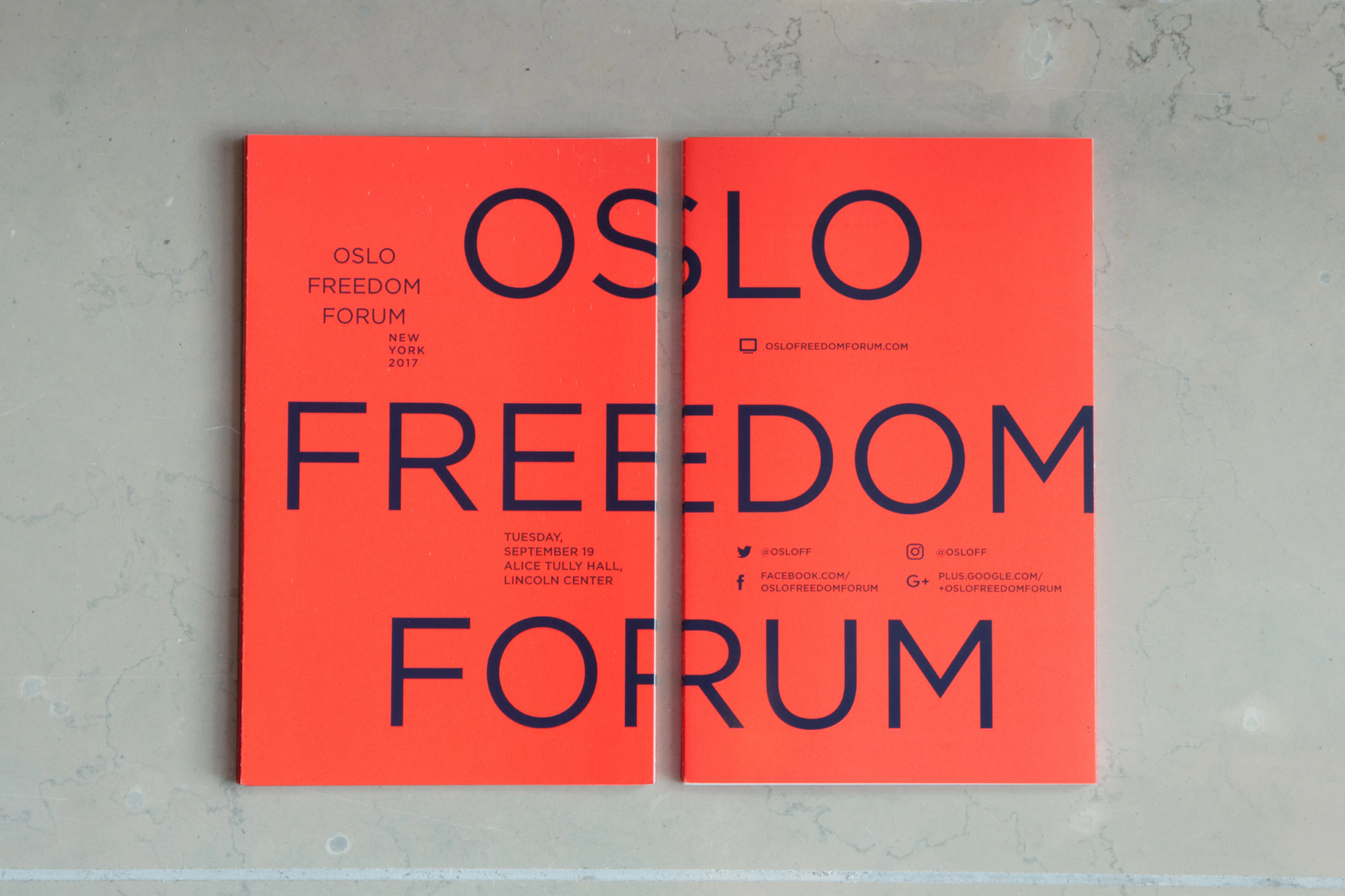 Image shows two books side-by-side, one showing the front and one showing the back. Across it reads OSLO FREEDOM FORUM in navy blue text on a coral-orange background. 