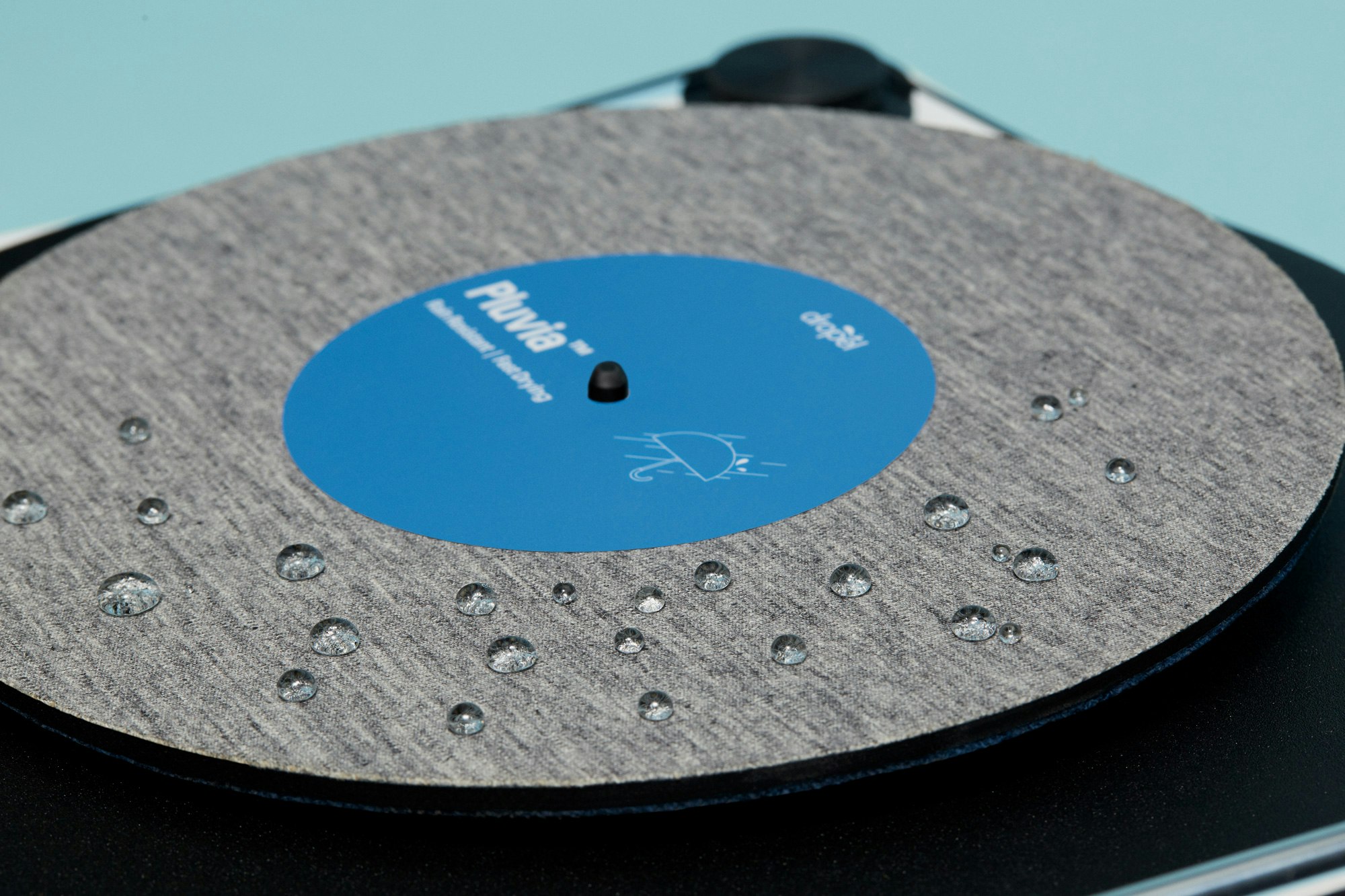 Photo showing a close up of the Dropel custom fabric record. To show the fabric is water proof about 15 drops of water are resting on top of the fabric.