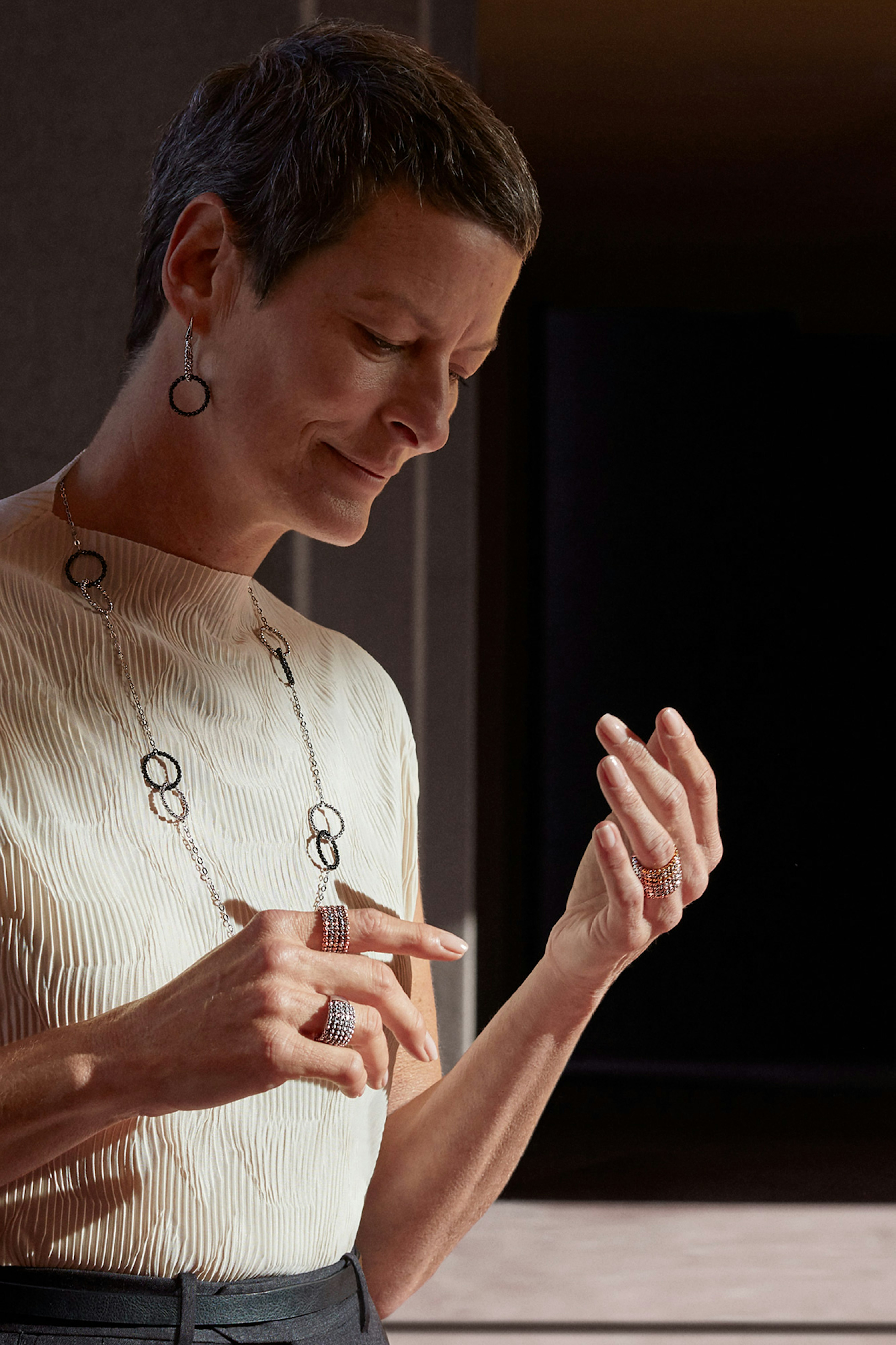 Image showing person wearing a cream top, necklace, earrings, and rings.