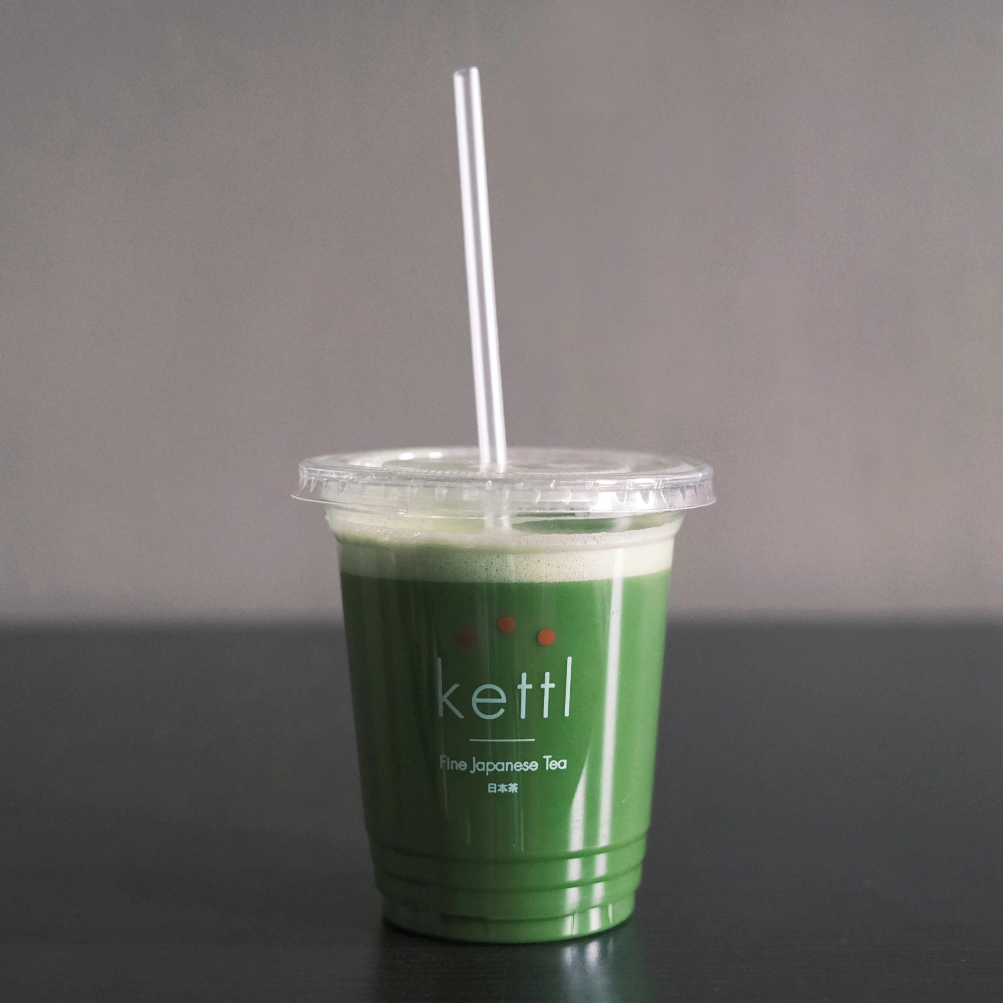 Image showing a clear take away cup with deep green iced matcha inside.