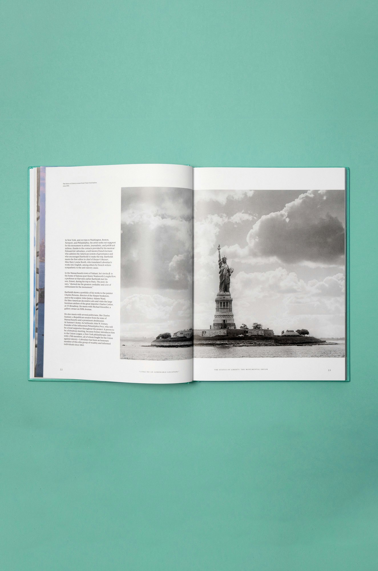 Image showing the book open to a page of a black and white photo of the statue of liberty. The book is lying on a green seamless.