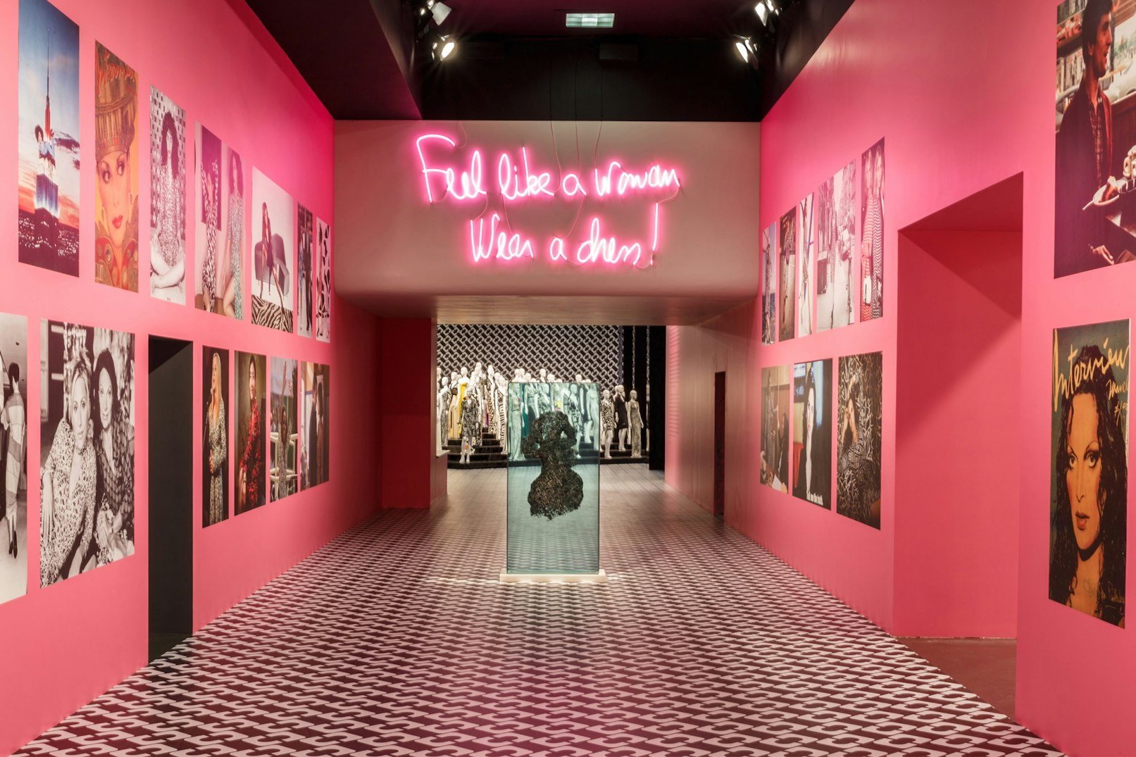Image showing part of the interior of the LACMA museum with the DVF exhibit. The walls are hot pink and the floor is covered in one of DVF's classic black white patterns.