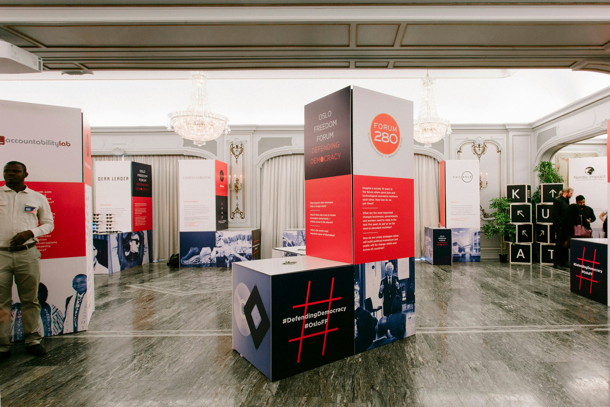 Image shows L-shaped installations in a ballroom setting. They are covered in blue-toned images, text, and infographics.