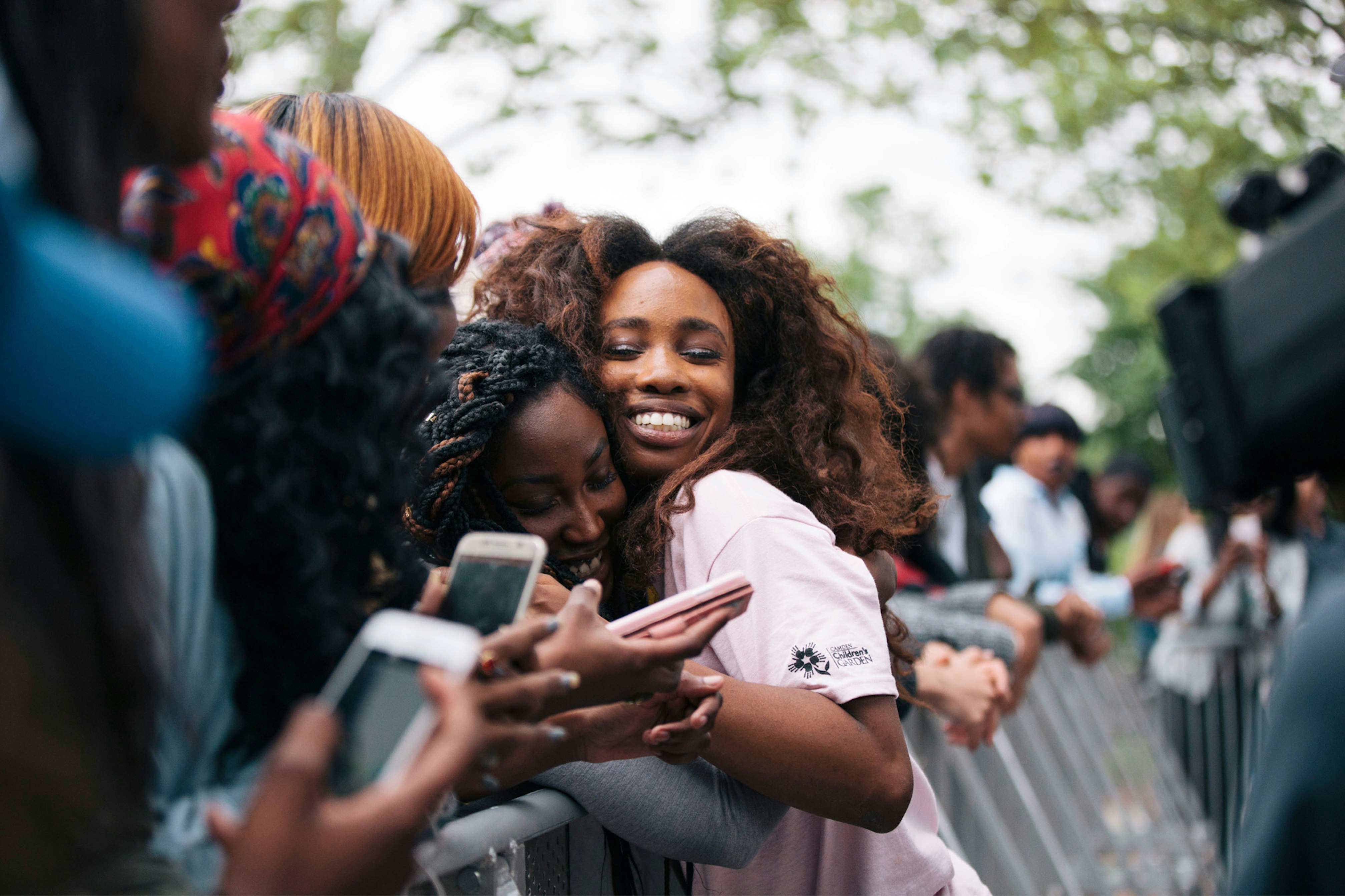 Image shows SZA smiling and hugging a person in the front row of a crowd. 