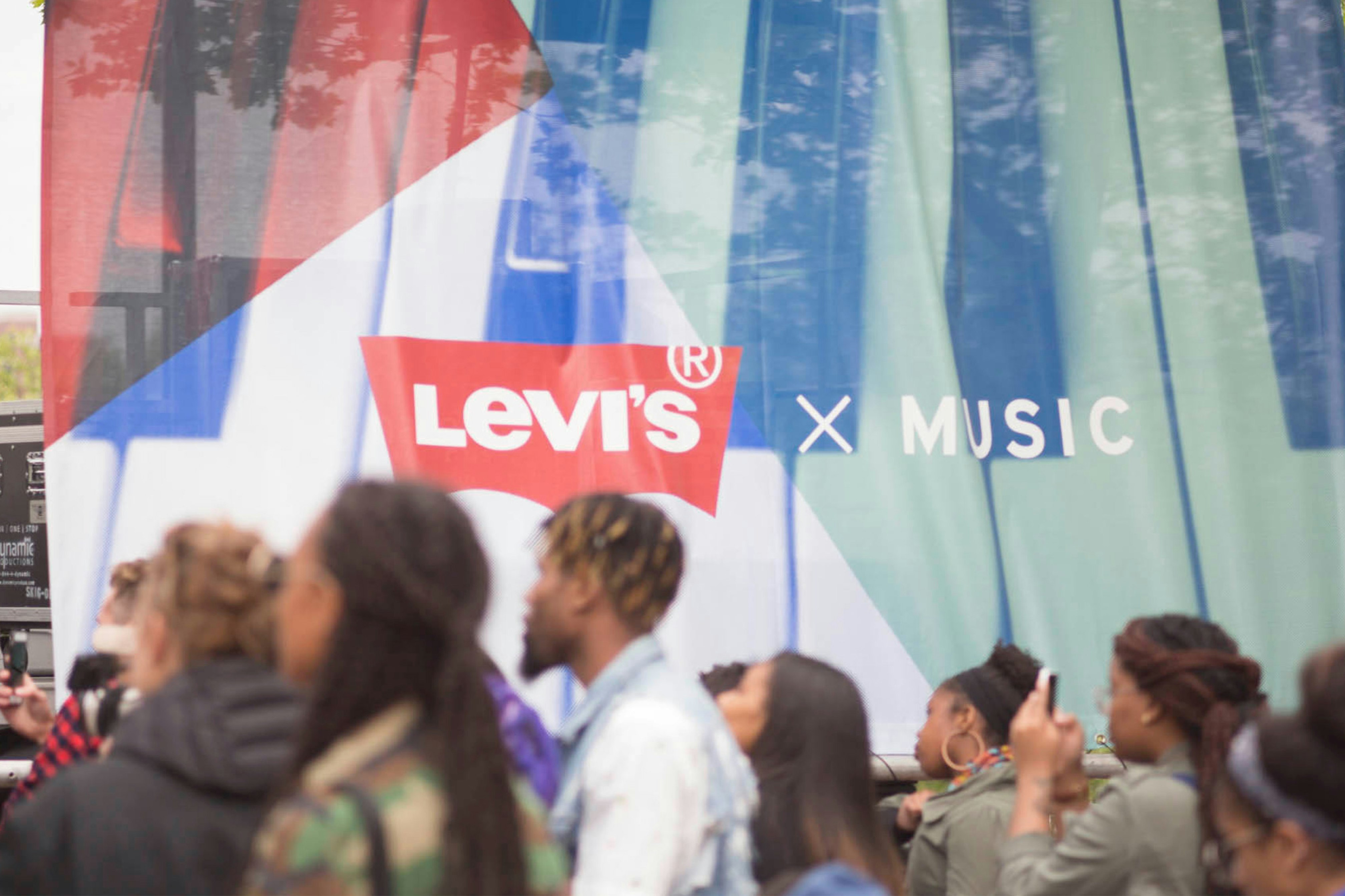 Image shows a crowd of people in the foreground and a banner that reads LEVI'S X MUSIC on it. 