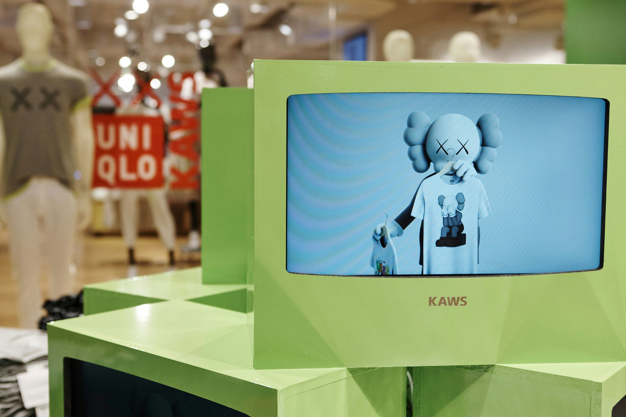 Image showing close up of in-store details showing light green paper television screens with KAWS image inside.