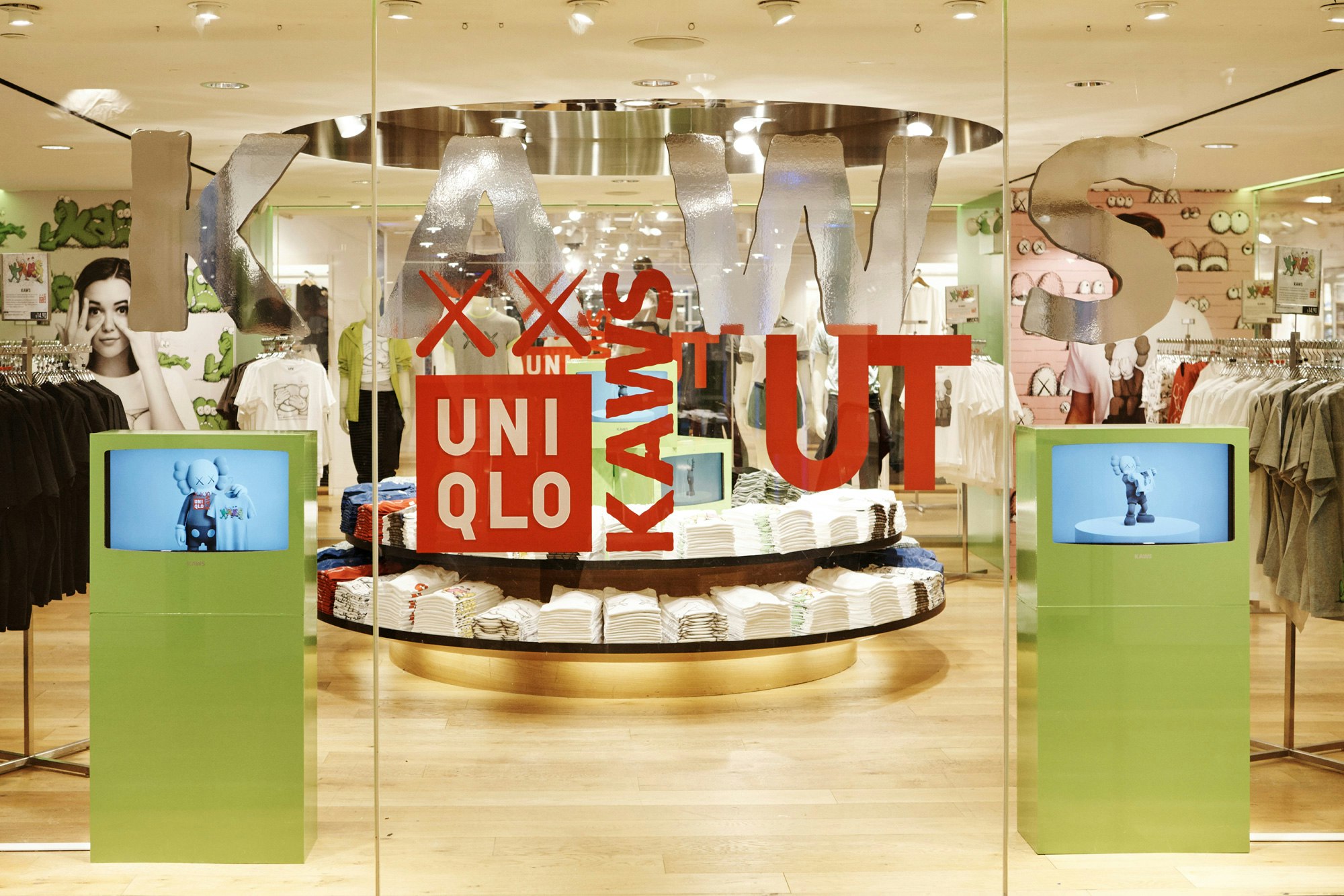 Image showing details from the inside of the Uniqlo store. On the glass door are red vinyls with the logo of Uniqlo and KAWS.