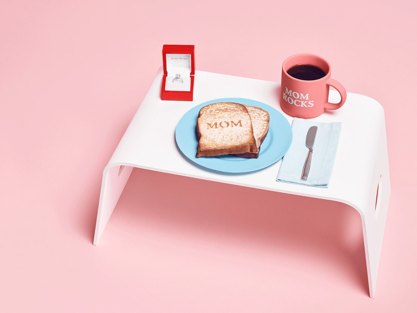 Image showing a tray with a cup saying 'mom rocks' and a plate with toast saying 'mom' and an open ring box with an engagement ring inside and an animation of a hand reaching for the ring.