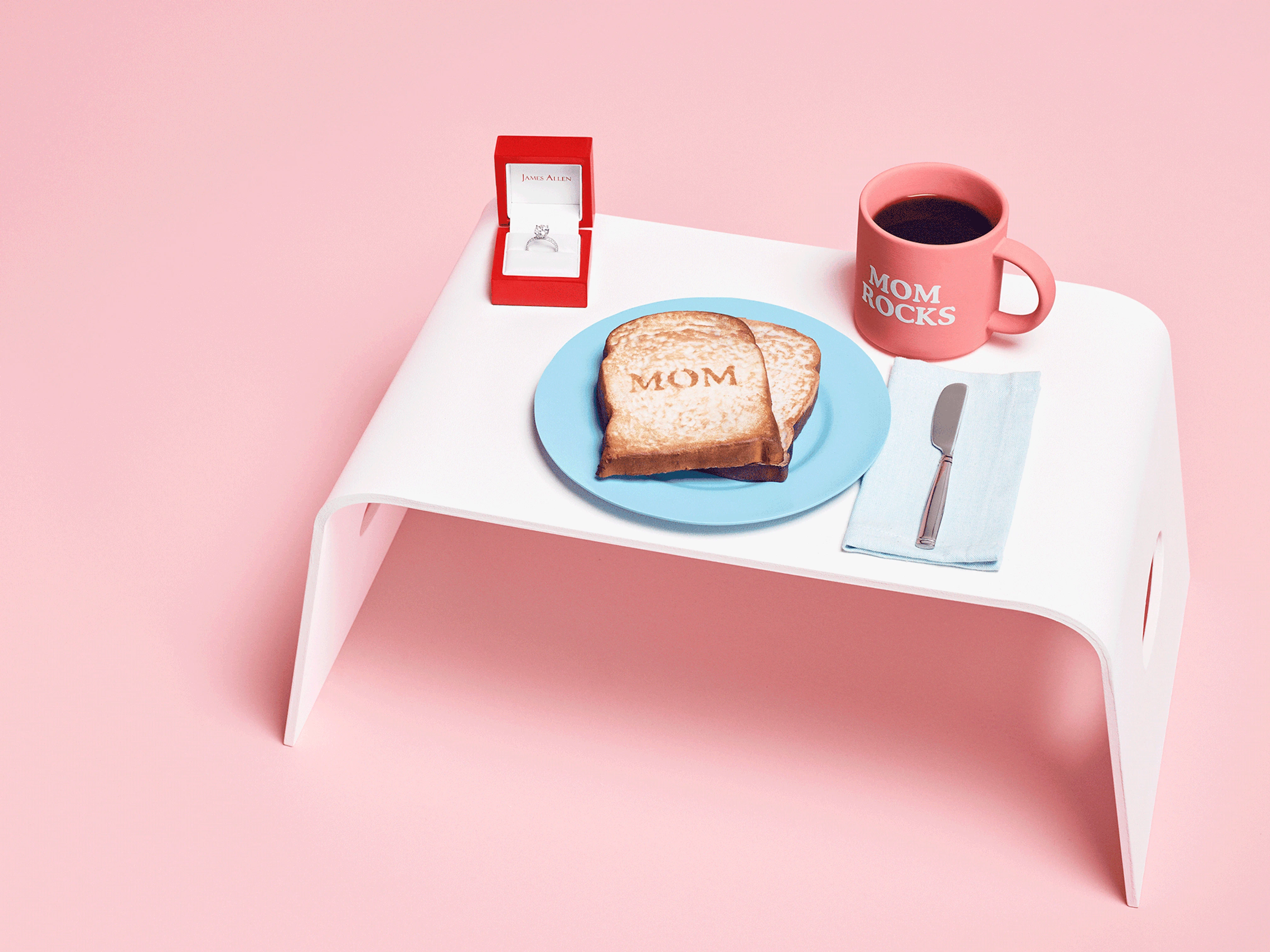 Image showing a tray with a cup saying 'mom rocks' and a plate with toast saying 'mom' and an open ring box with an engagement ring inside and an animation of a hand reaching for the ring.