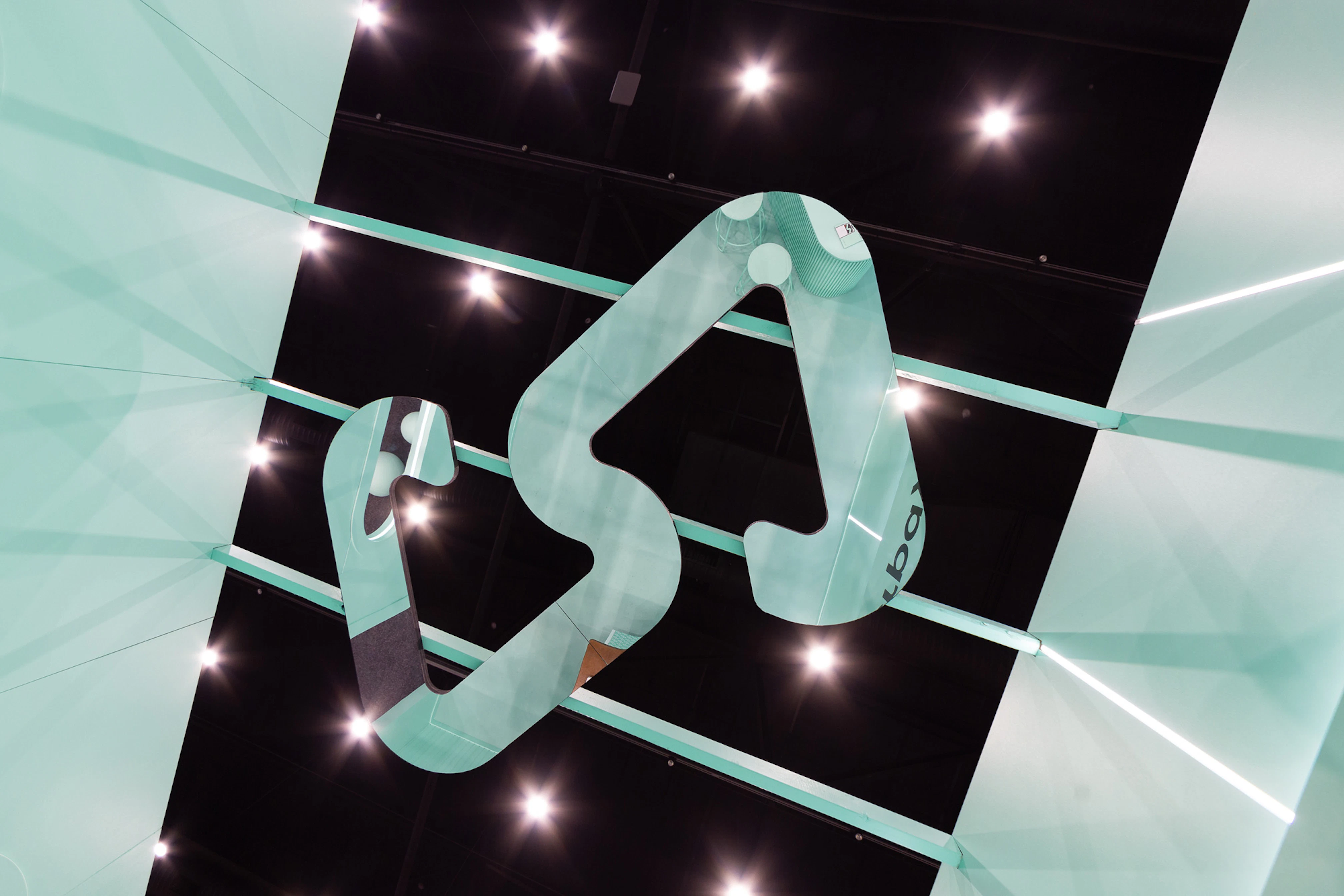 Image showing the ceiling of the Afterpay Bondi Mint expo booth. There is an oversized mirror version of the logo reflecting the mint booth and behind the mirror logo there is the black ceiling of the expo hall with spot lights looking like stars.