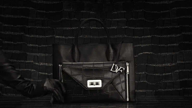 An animation showing hands in long black gloves unzipping the front pouch of a black bag with the DFV hardware hanging from the handle.