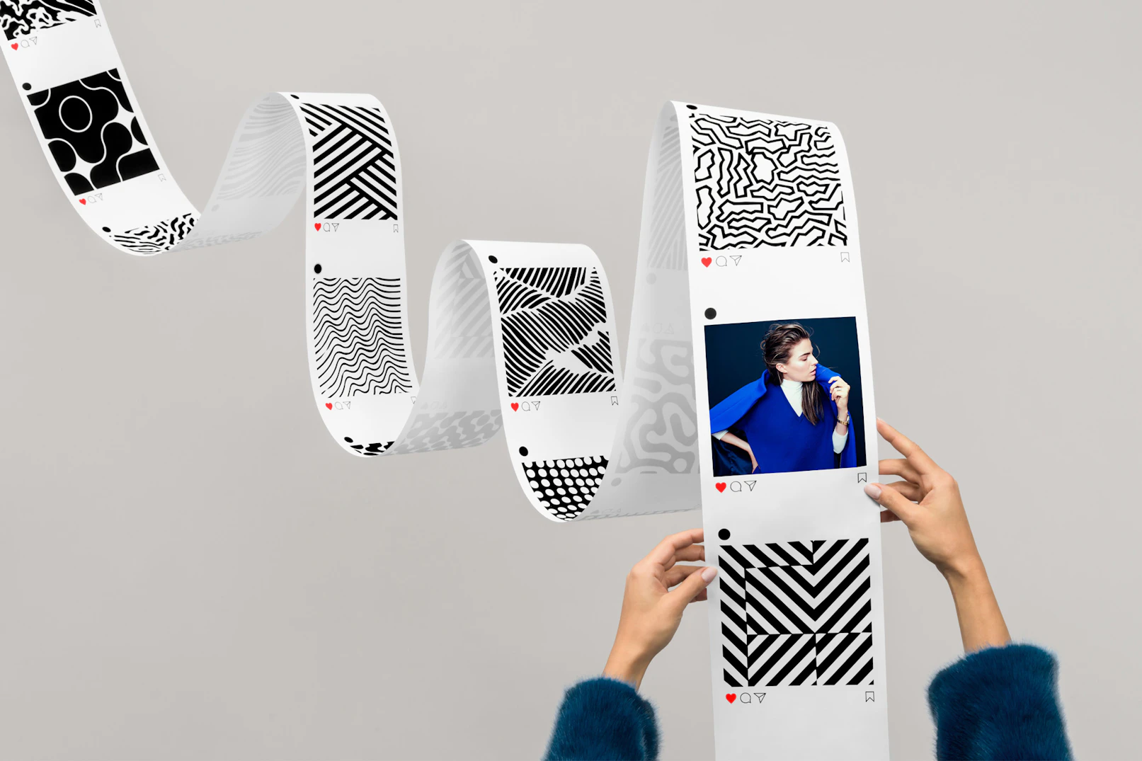 Image shows an Instagram feed formatted on a long flowing piece of paper, like a scroll, held by two hands in a fuzzy jacket.