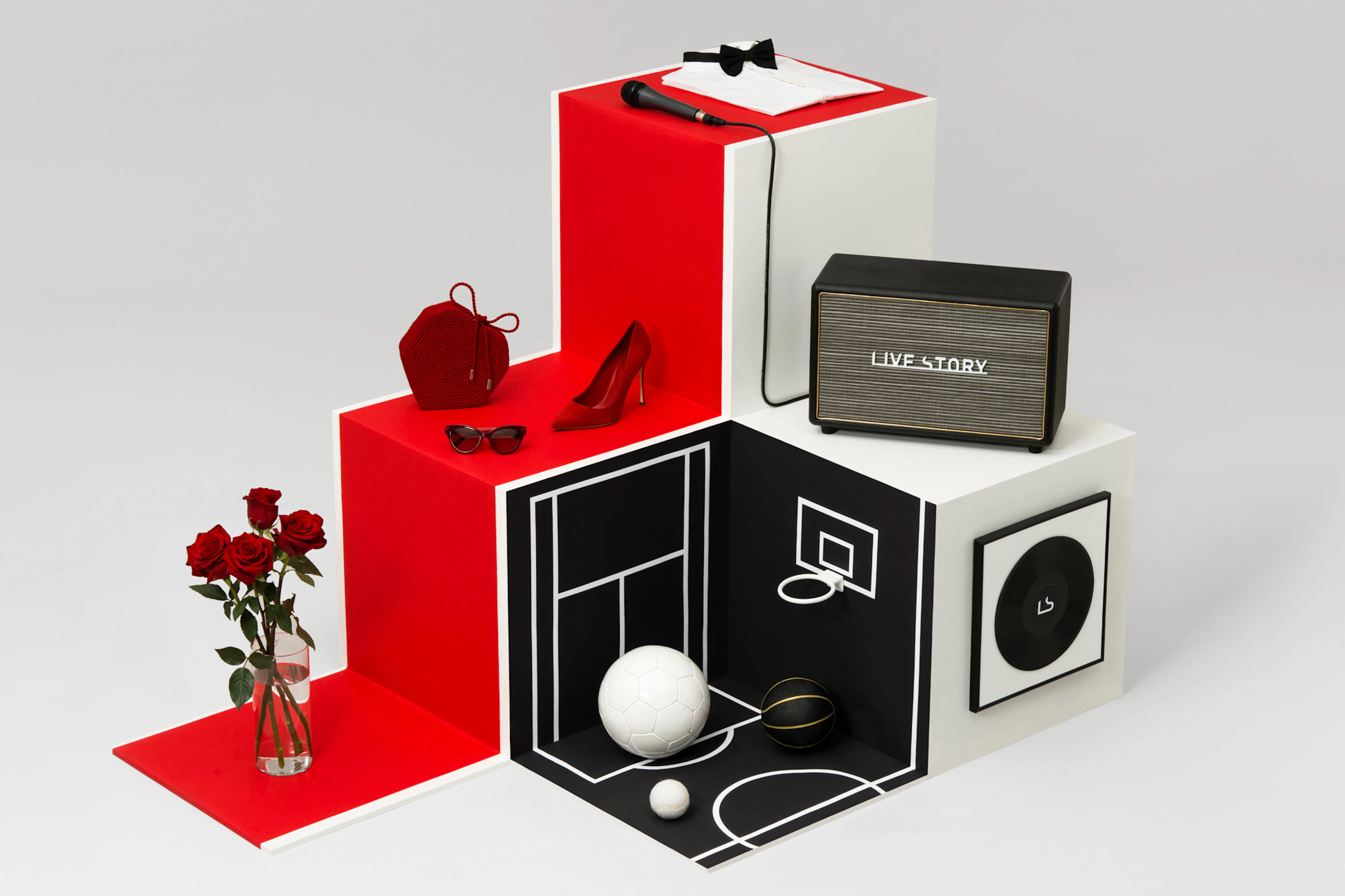 Image shows boxes created a scene including red steps with roses, shoes, sunglasses, and a small basketball court, and a speaker. 
