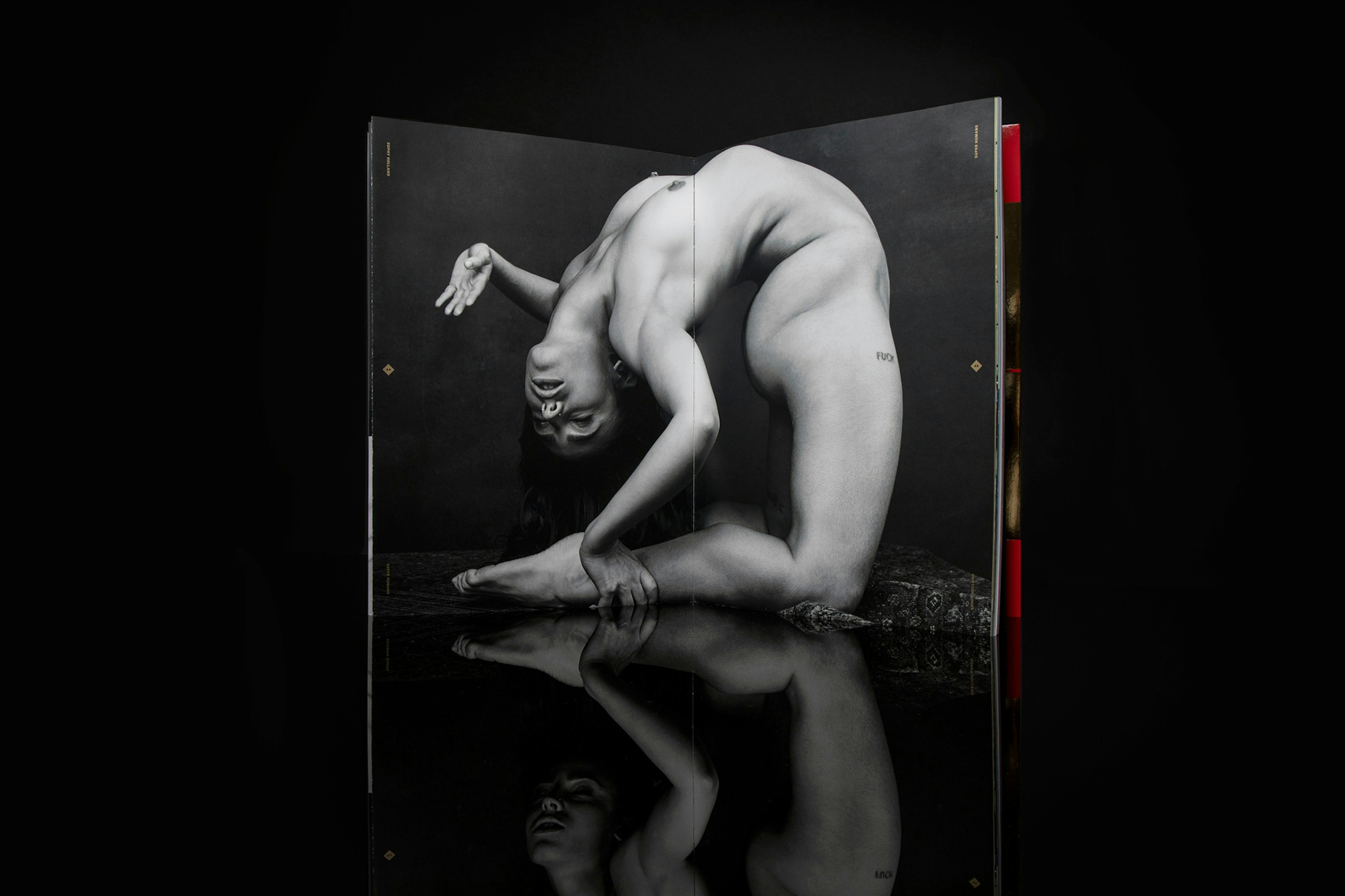 Image shows a book open to a black and white photograph of a person bending over backward to grab their ankle. 