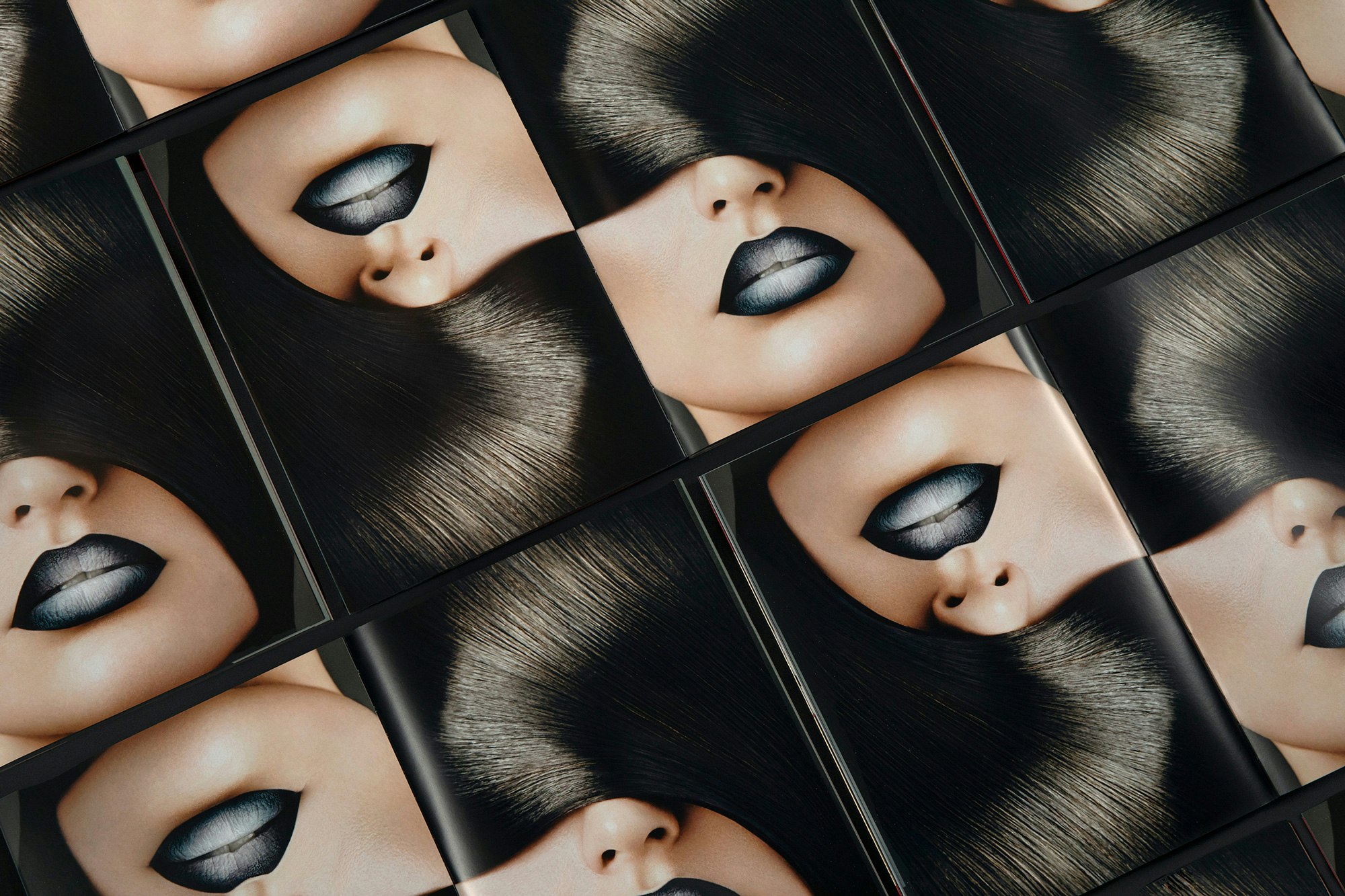 Image shows multiple books open to a spread that is a close-up of a face with sleek dark hair covering the model's eyes, and the model has black lips.