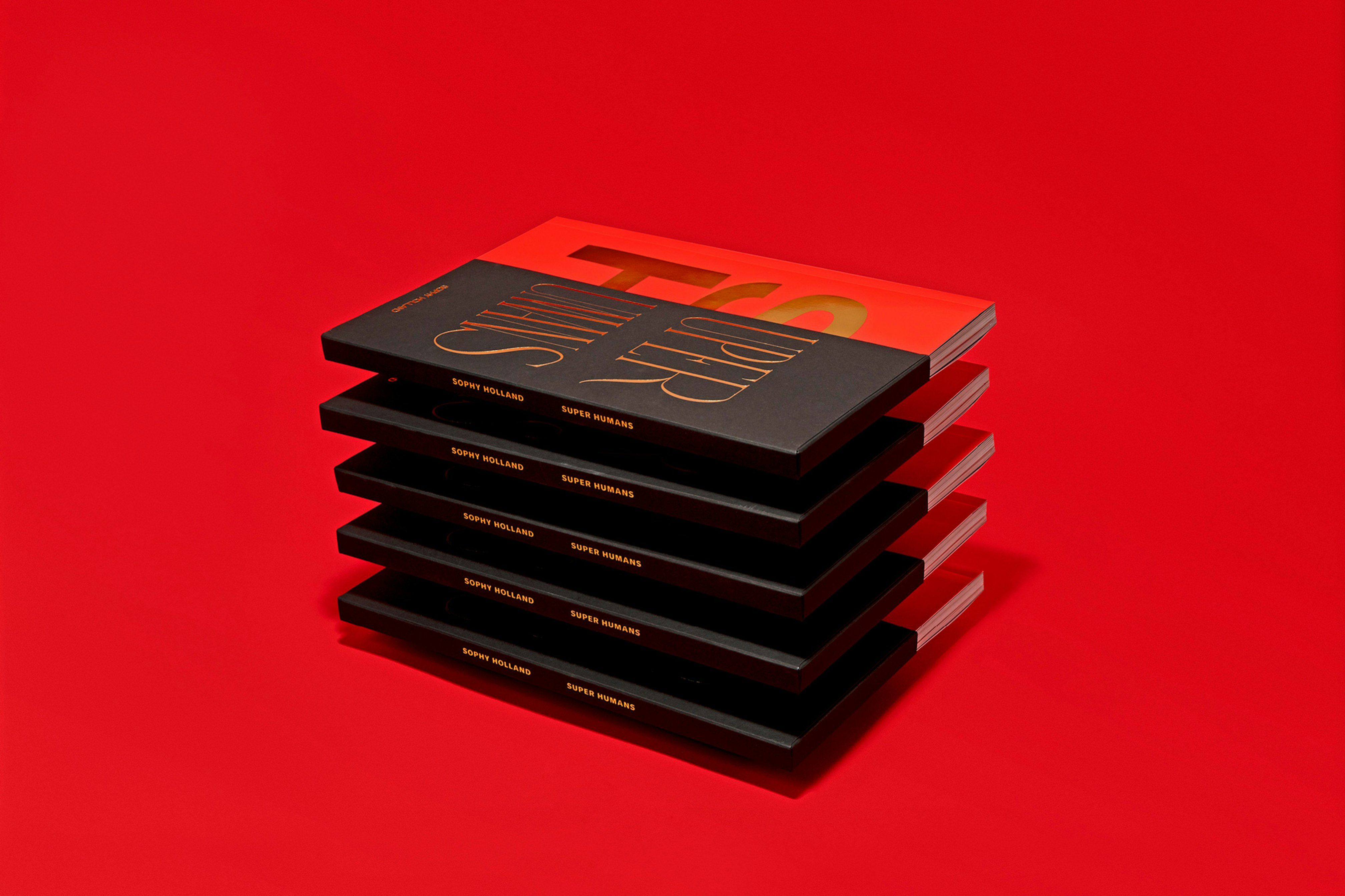 Image shows a stack of red and black books hovering, not touching one another, on a red background. 