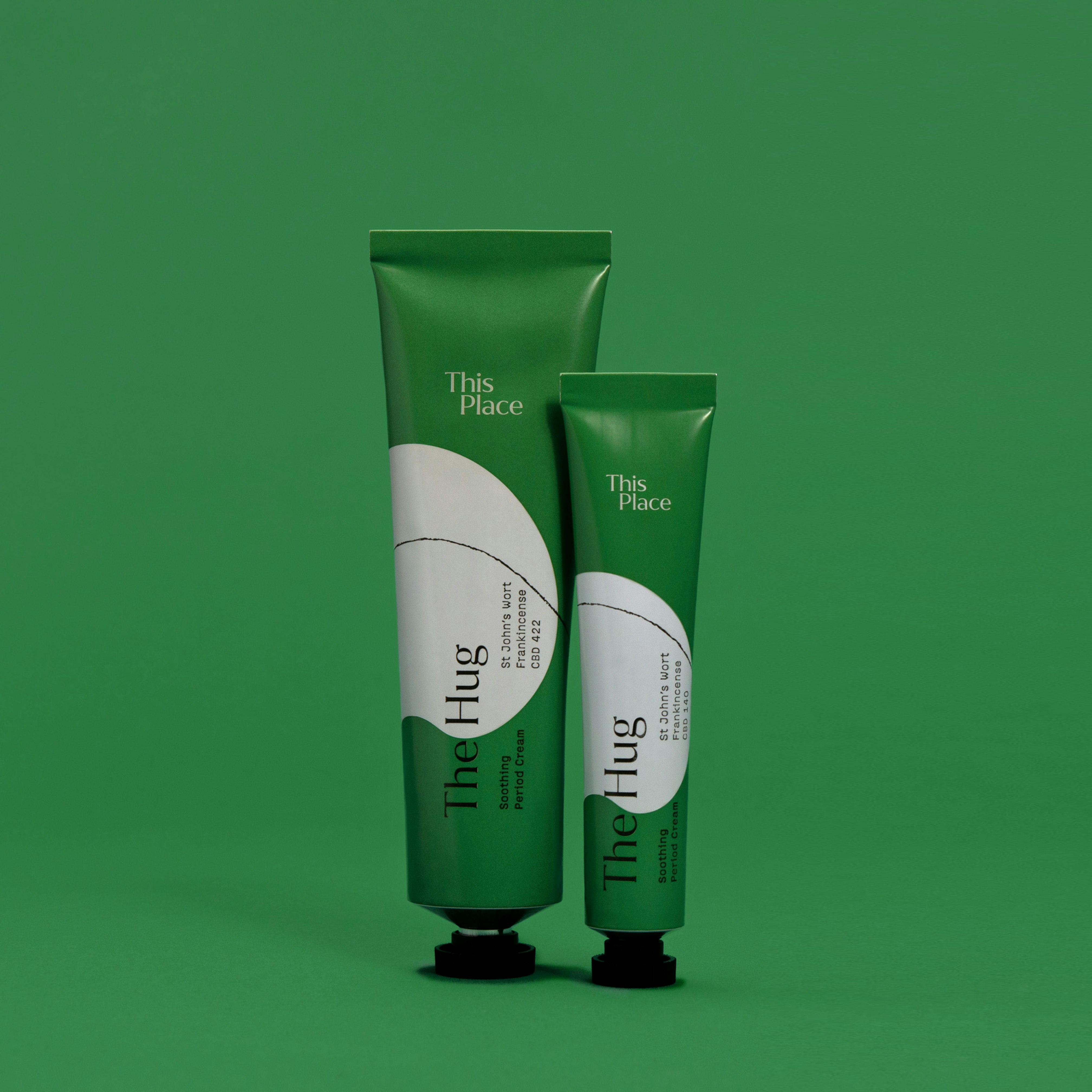 Photo showing two green tubes on a green seamless. The Hug is written across the tubes in black type.