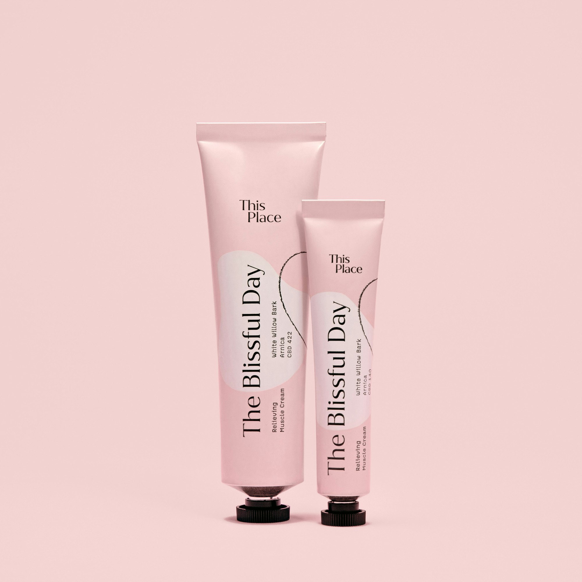 Two pink tubes standing on a pink seamless. The blissful day is written in black across the tubes.
