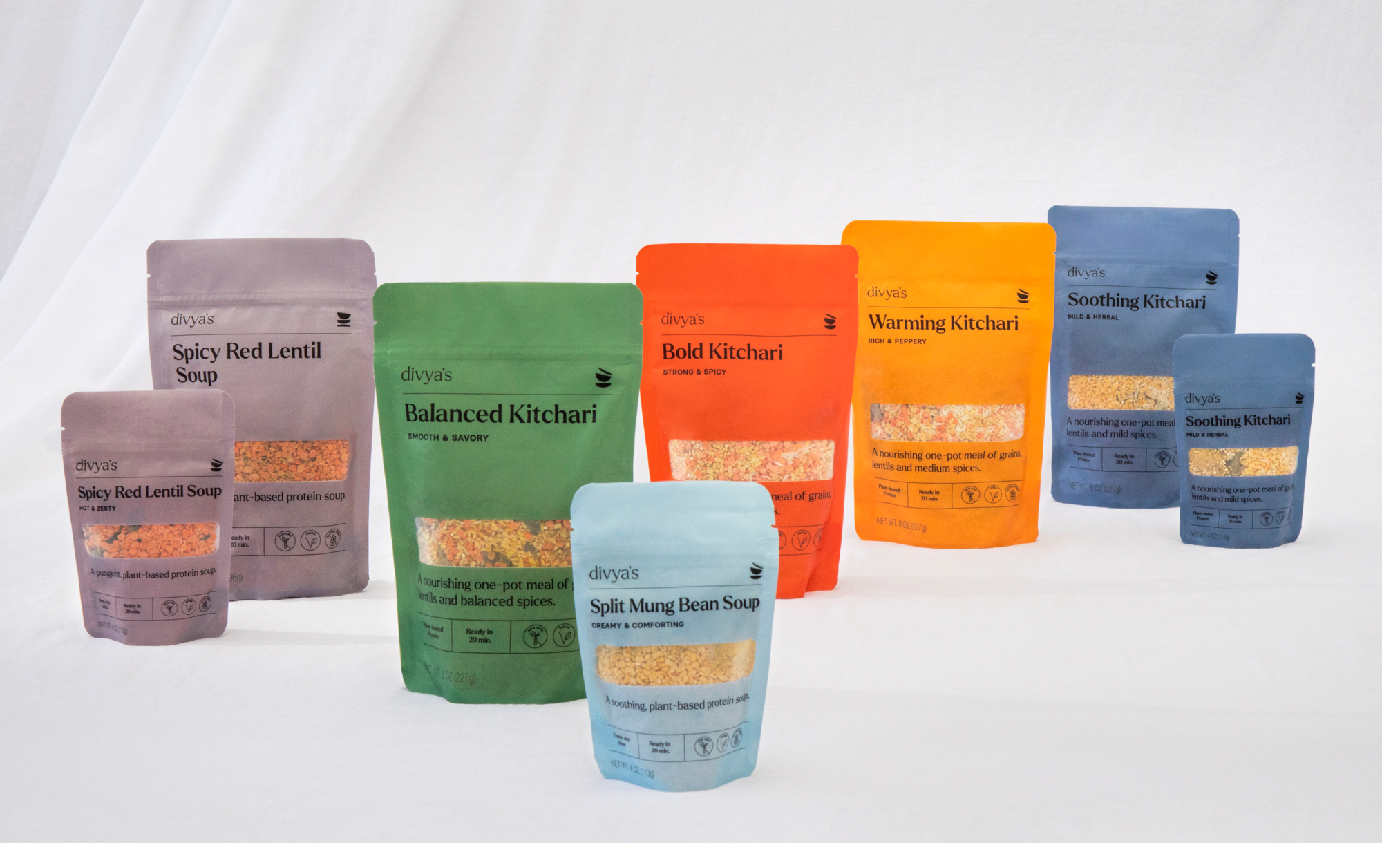 Divya's All Packagings in gray, green, light blue, red, orange, and medium blue on a white fabric background.