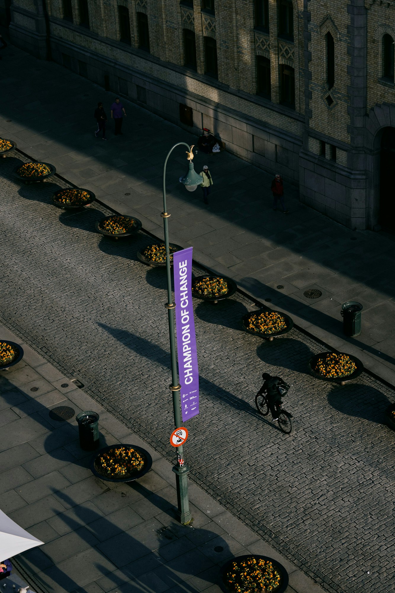 Purple street banner on a street with a person riding a bike next to it.