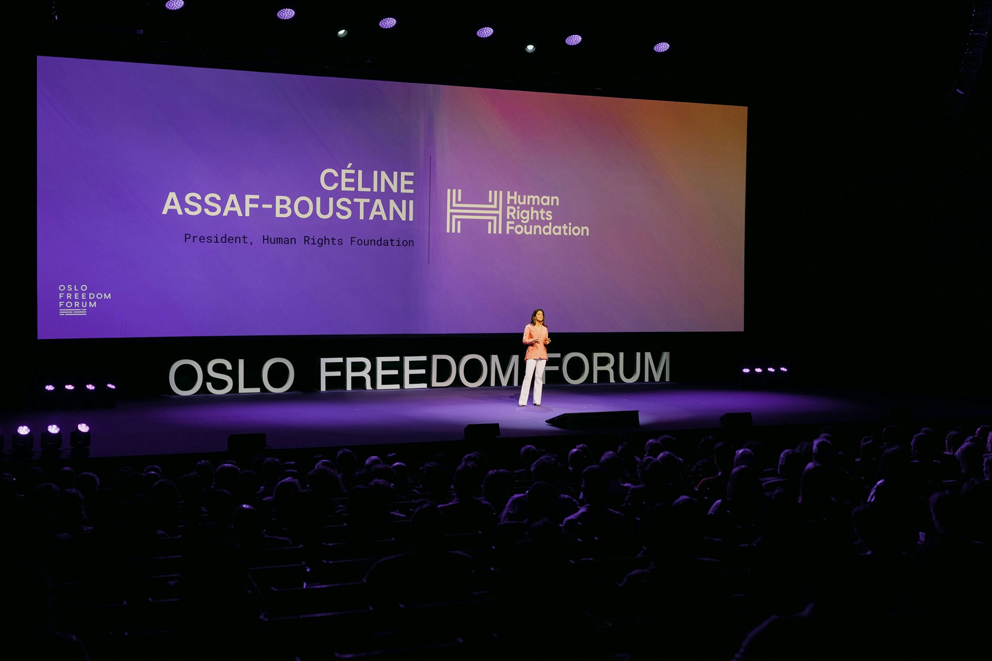 A person speaking on stage with the screen on the back saying "Celine Assaf-Boustani, President, Human Rights Foundation" next to Human Rights Foundation logo in white.