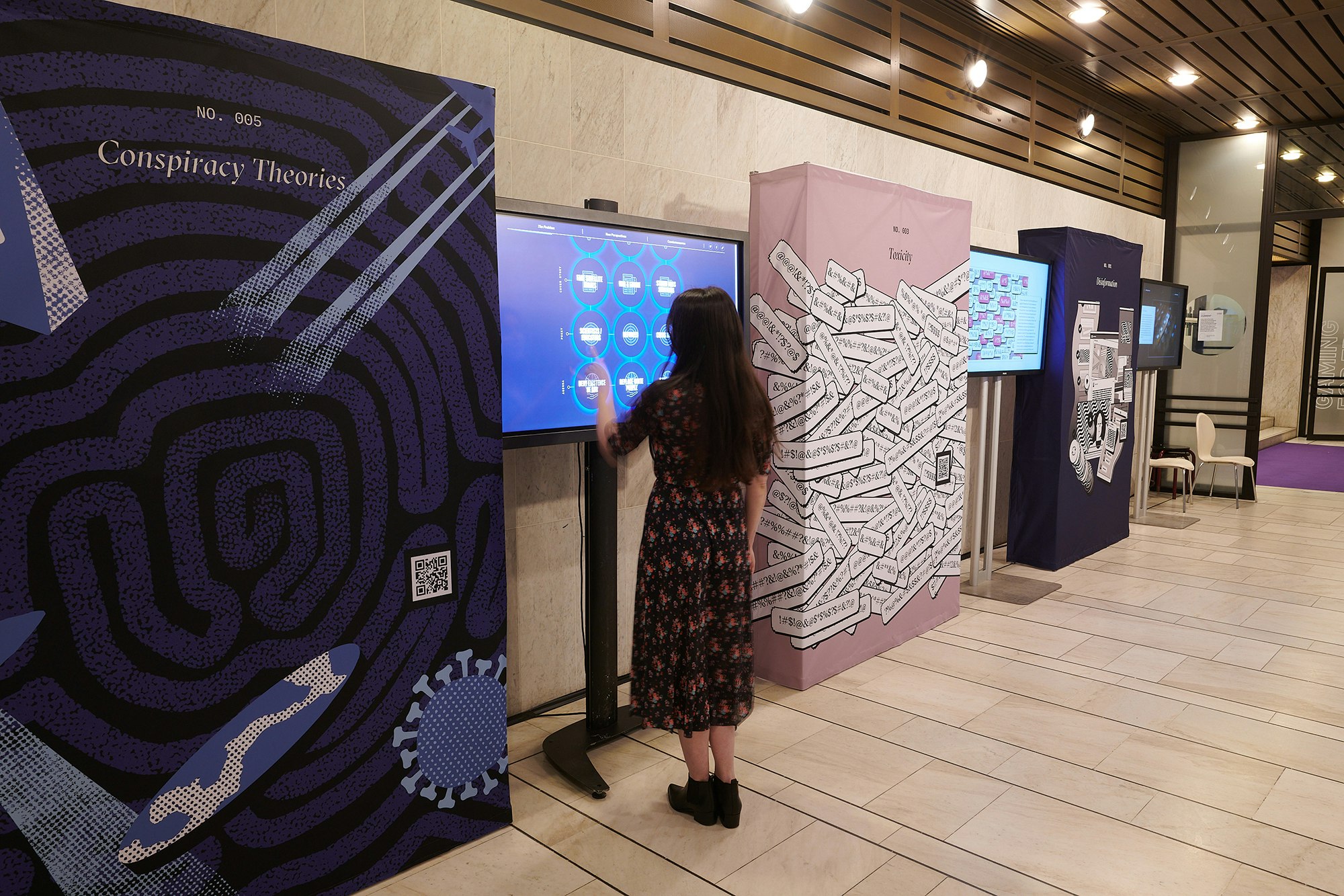 A person is interacting with the screen. Next to her are hop ups with artworks from Jigsaw articles.