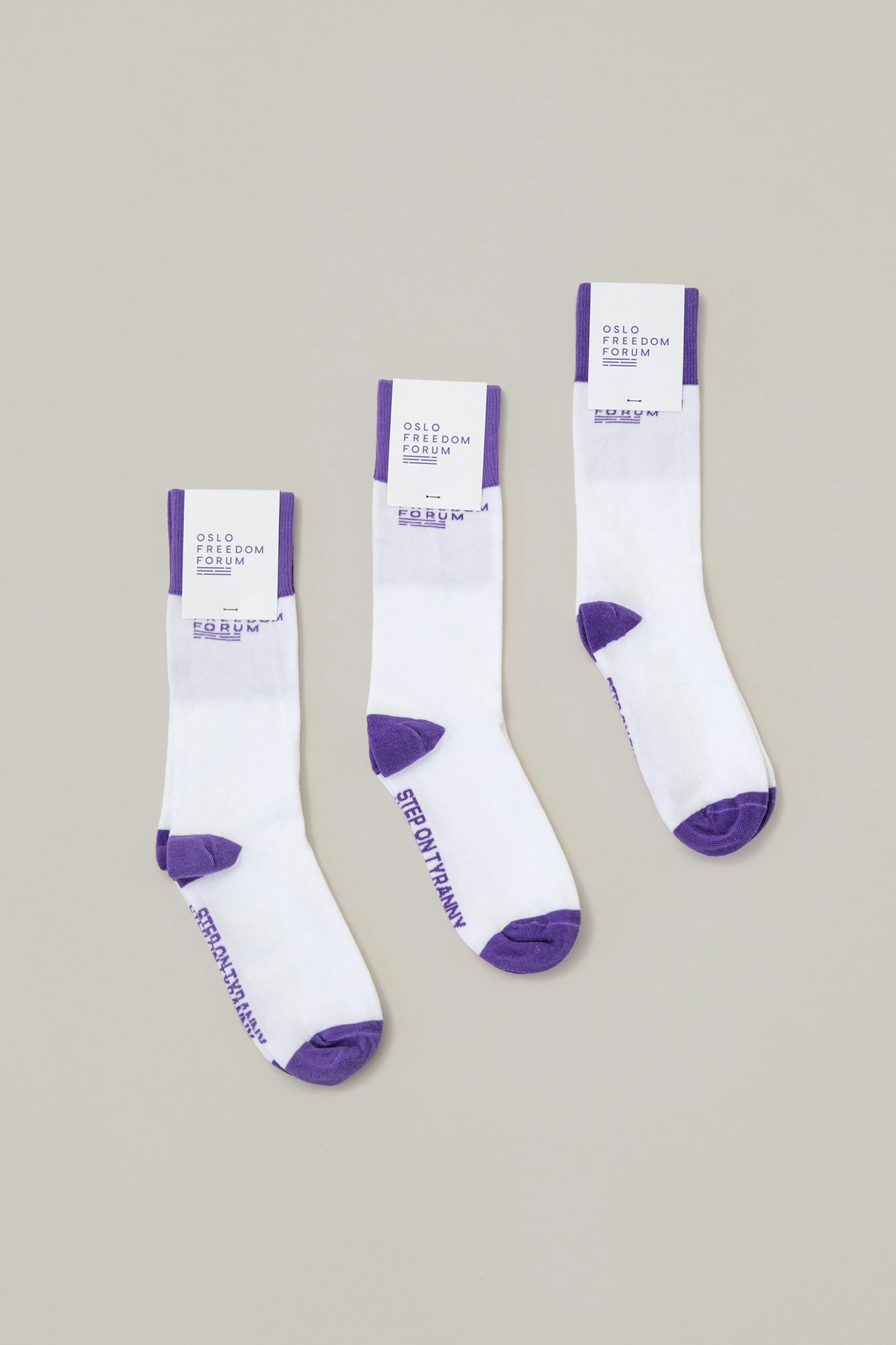 Oslo Freedom Forum socks in white with the tips in purple. At the bottom of the socks saying "step on tyranny".