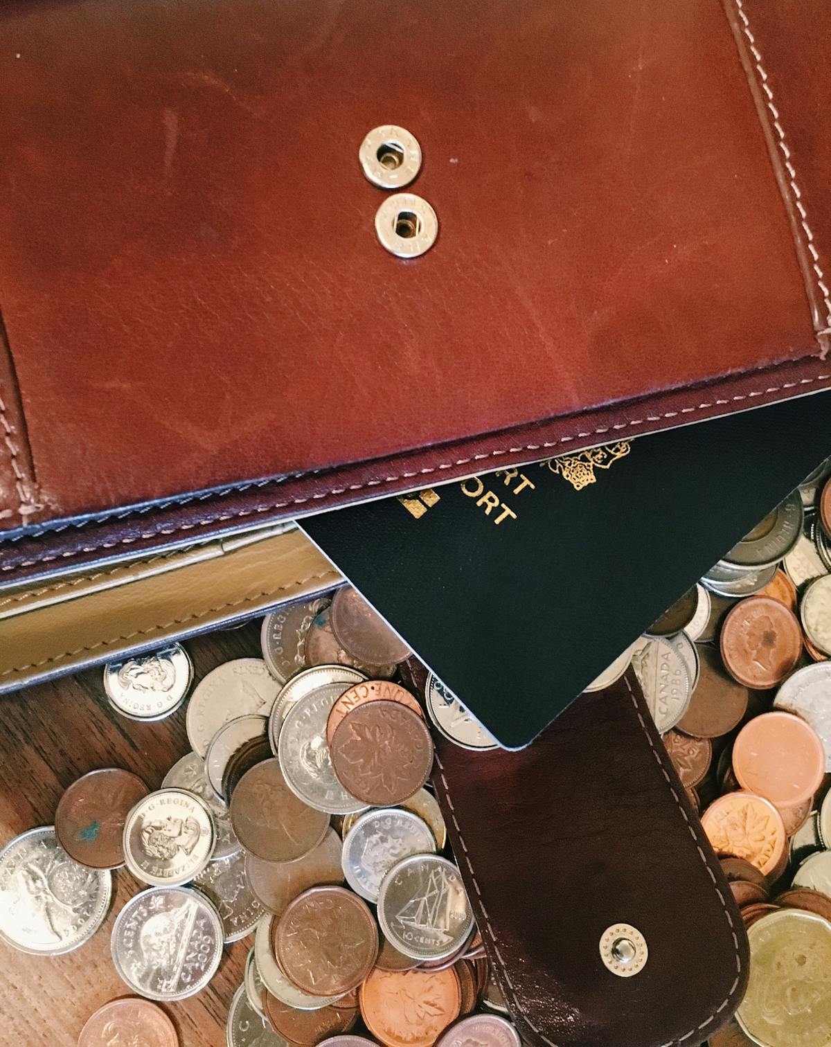 A leather satchel that spills many coins and a passport - Photo by pina messina on Unsplash