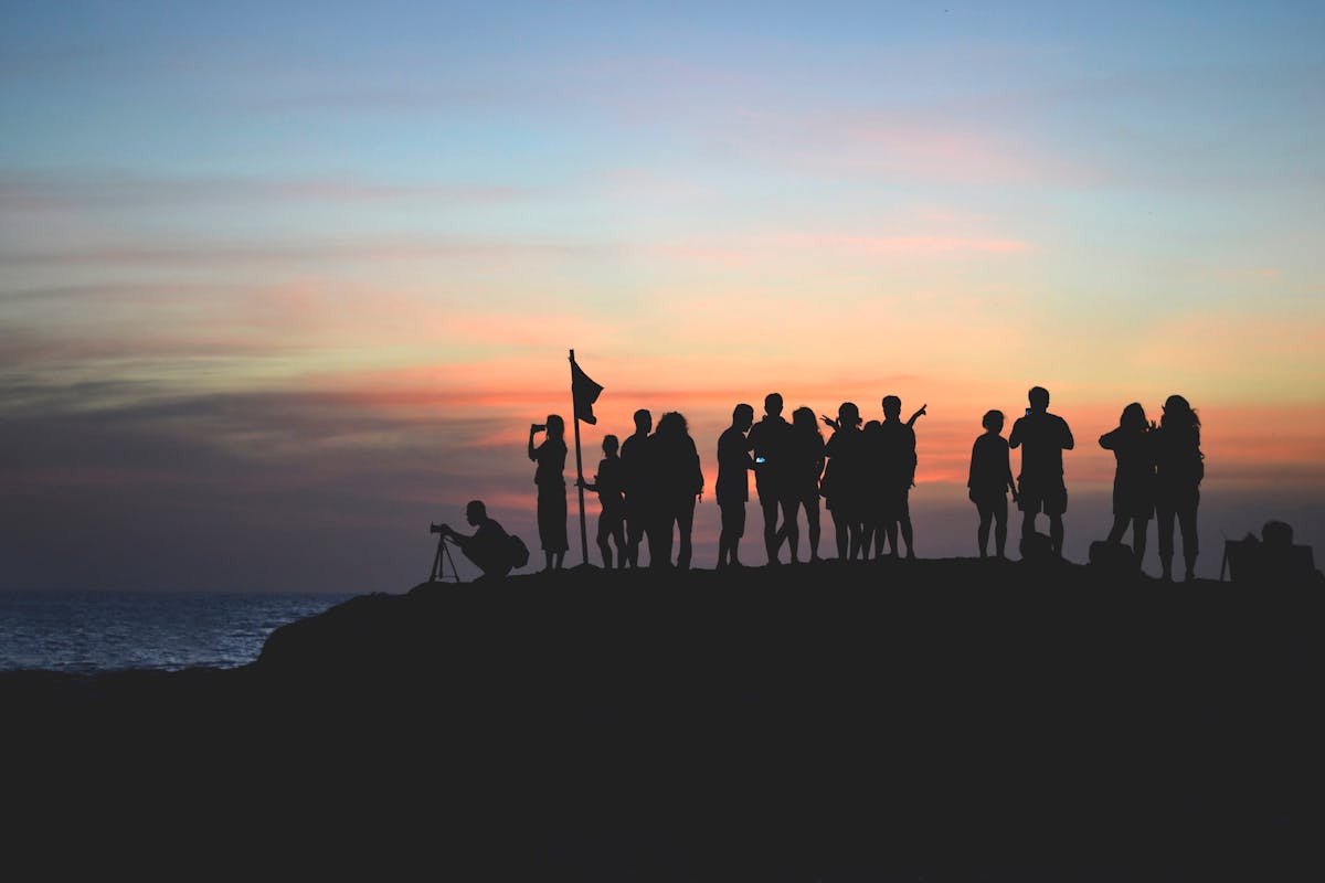 Plan d'une équipe qui a grimpé un rocher au coucher de soleil - Photo by Javier Allegue Barros on Unsplash