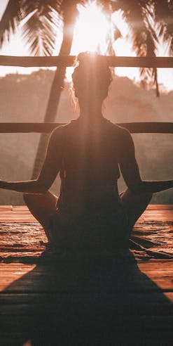 Woman doing yoga and watching a sunset