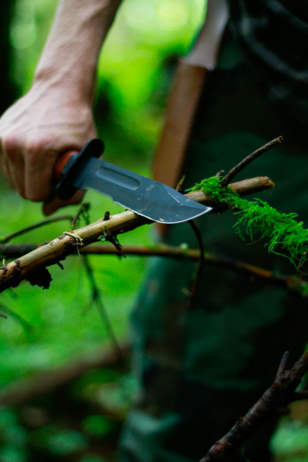 A man with a survival knife cuts a branch - Photo by 2 Bro’s Media on Unsplash