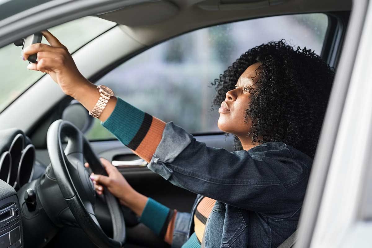 Femme dans une voiture réglant son rétro