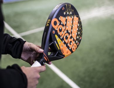 Mains qui tiennent une raquette de padel adidas