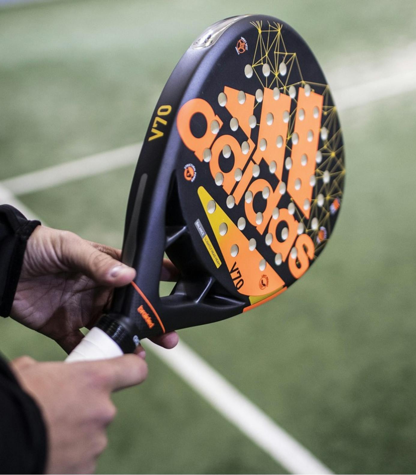 Mains qui tiennent une raquette de padel adidas

