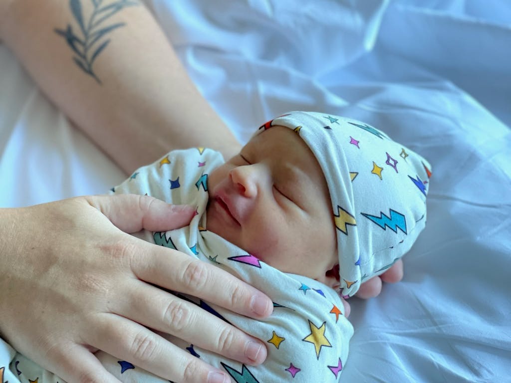 Baby Miles resting in a swaddle covered in colorful stars and lighting bolts.