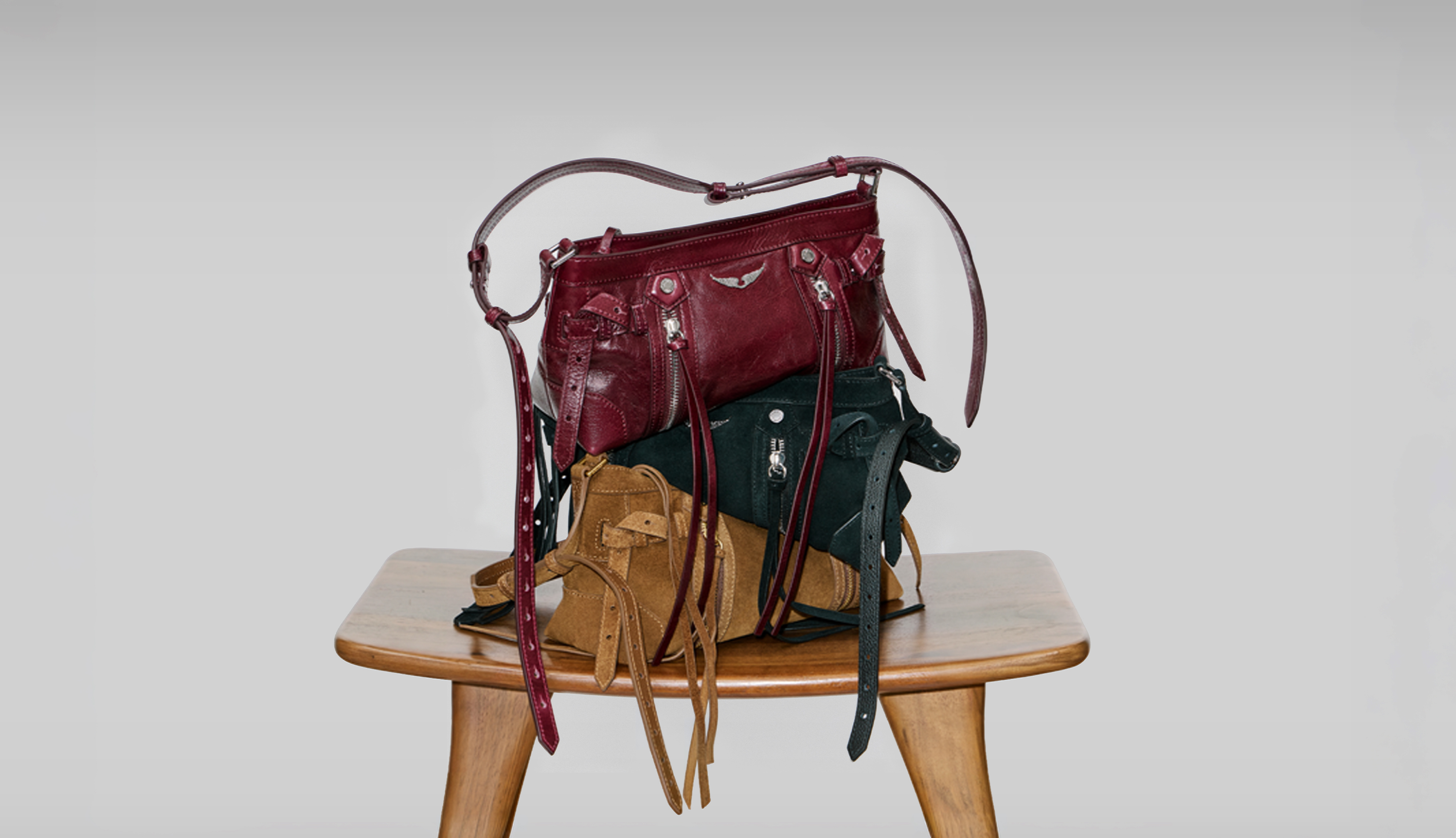 Tres bolsos Madison apilados sobre una silla de madera