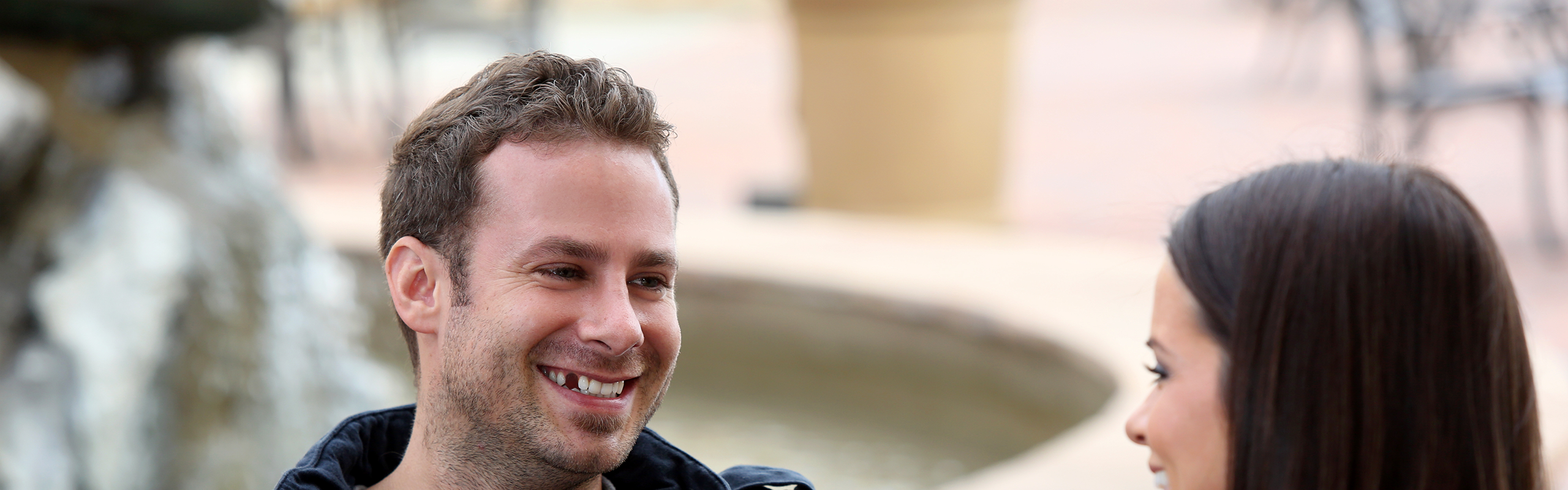 Mann mit Zahnlücke lacht eine Frau an - Zahnbehandlung Kostenübernahme von den Zahnzusatz-Experten