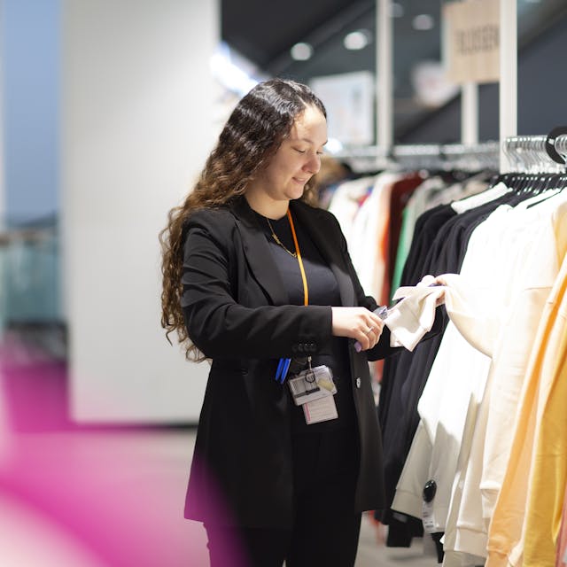 A person adds a clothing tag to a long-sleeved top