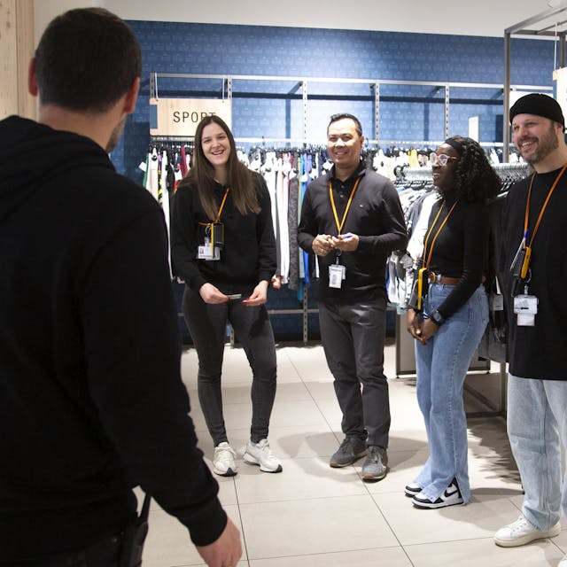 A group of people stand and laugh together on a shop floor. 