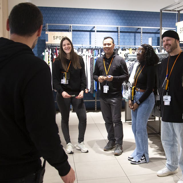 A group of people stand and laugh together on a shop floor.
