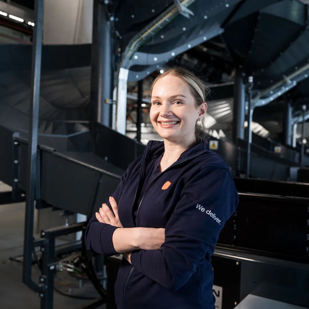 A women standing at a Logistics centre in front of the slides for parcels.