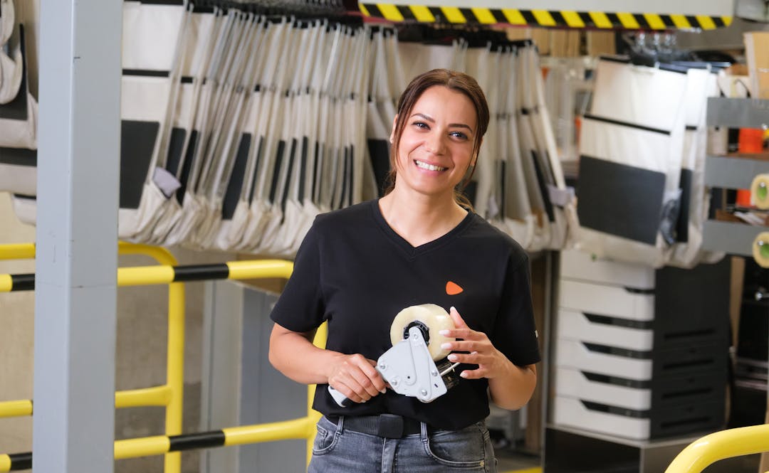 A person standing while holding tape that will be used to seal packages