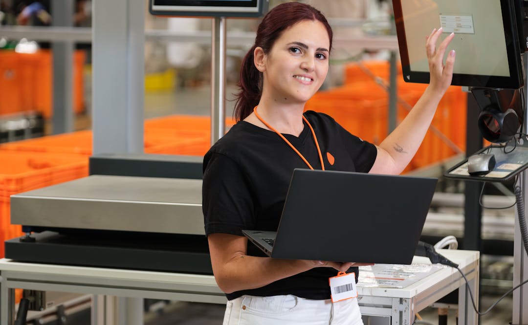 A person holding a laptop and touching an interactive screen