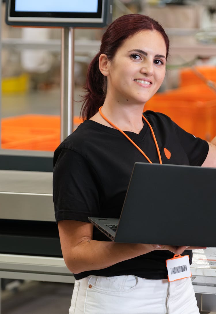 A person holding a laptop and touching an interactive screen